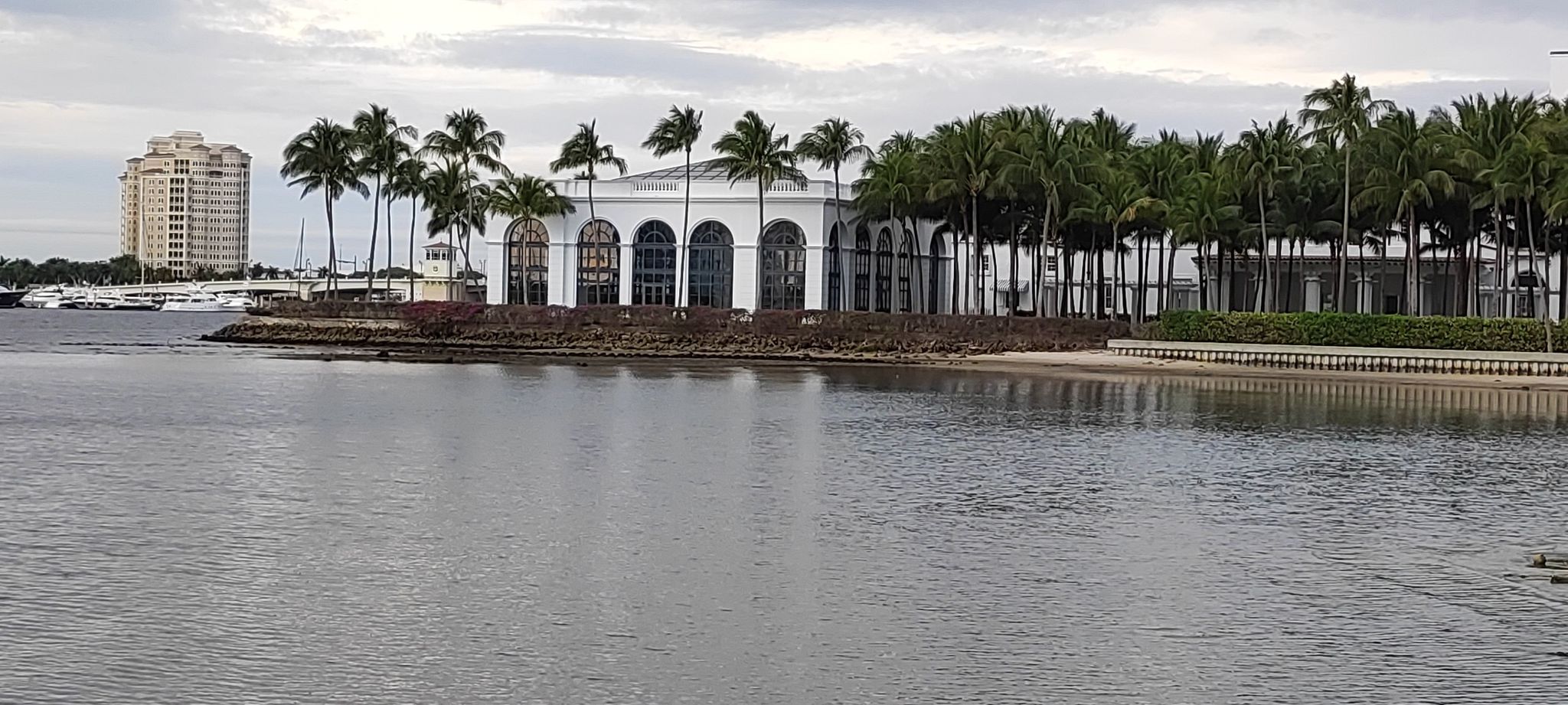 Waterfront buildings, palm trees, and a distant city skyline under cloudy skies. - East Coast Greenway: Palm Beach Loop