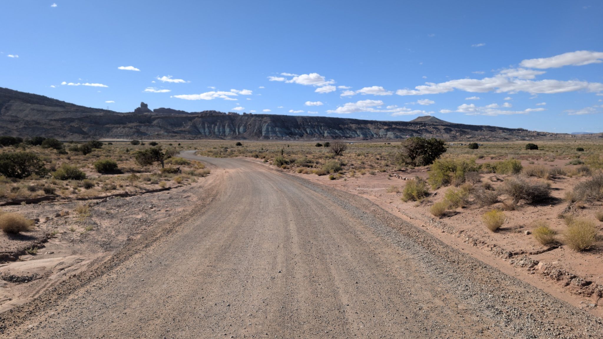 A long dirt road stretches through a vast desert under a bright blue sky. - Willow Springs Road
