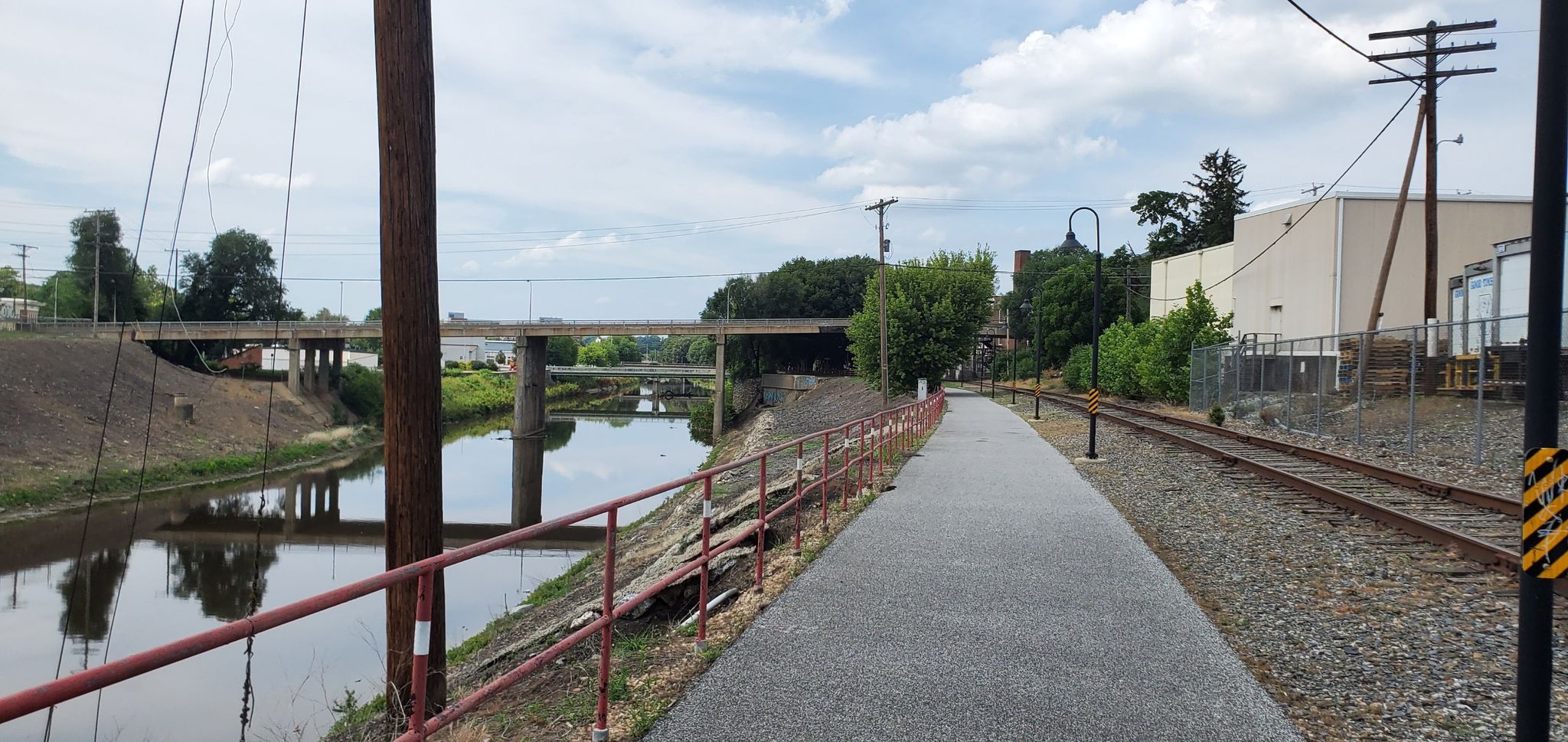 A paved path next to a river and railroad tracks, with bridges. - Running loop from York