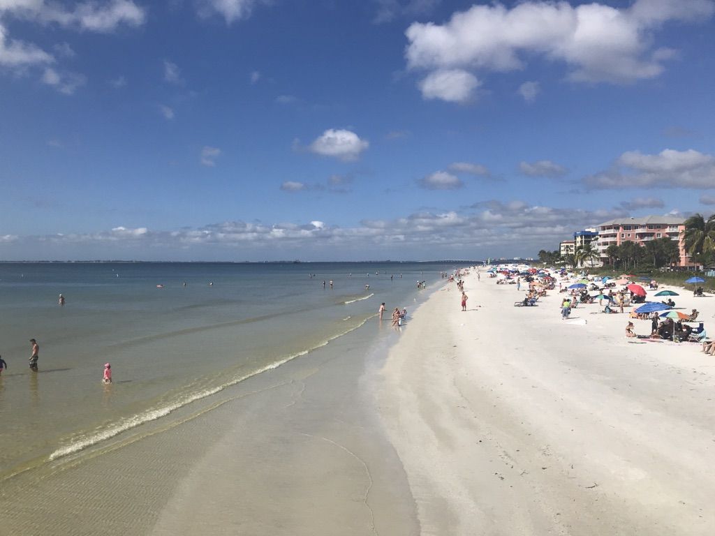 Sunny beach with many people swimming and relaxing under blue sky. - Fort Myers Beach Downtown – Fort Myers Fishing Pier loop from Fort Myers Beach