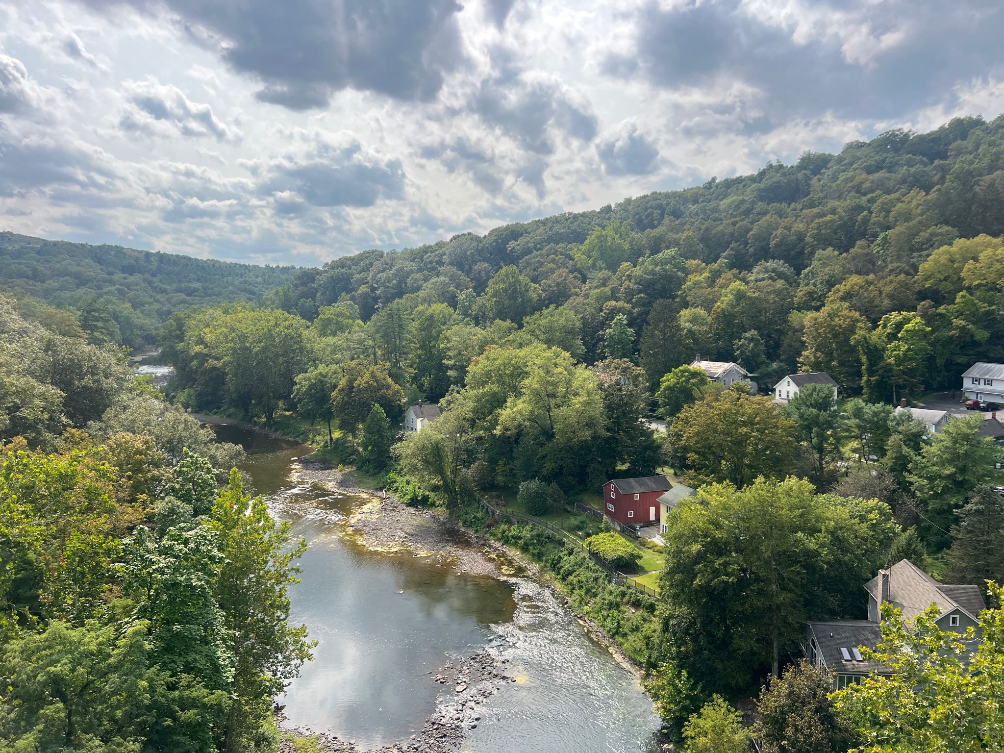 River winding through a green valley with houses under cloudy skies. - Wallkill Valley Rail Trail Loop