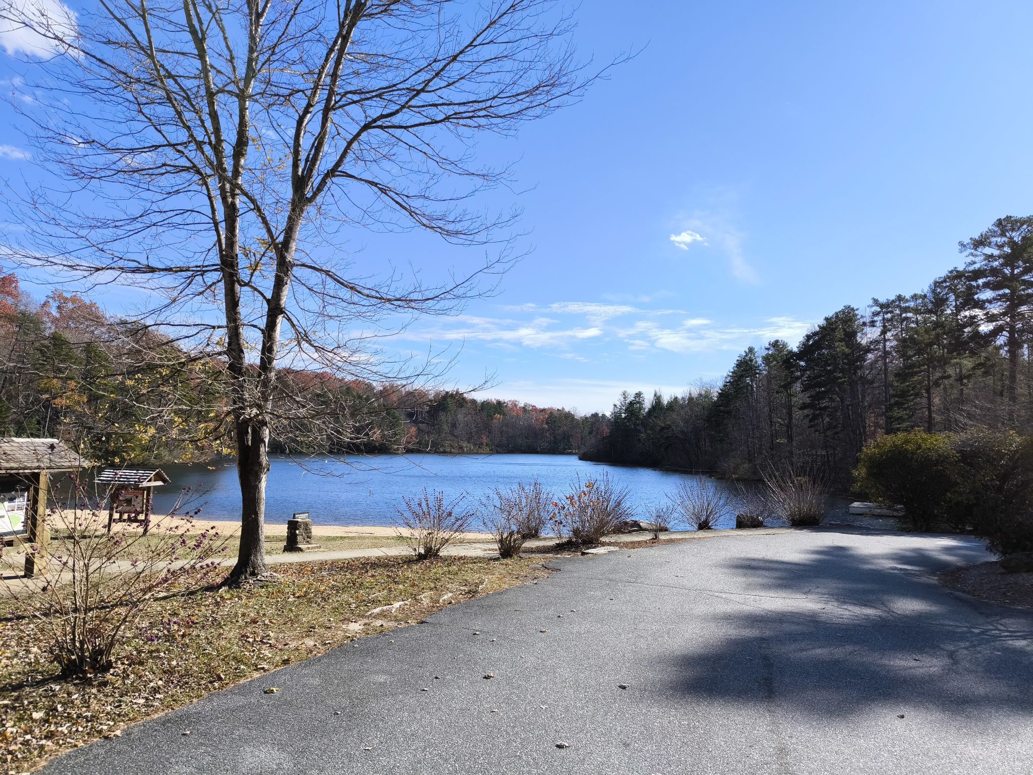Paved road leads to a blue lake surrounded by bare trees and evergreens. - Paris Mountain – Batson Mill loop from Table Rock State Park