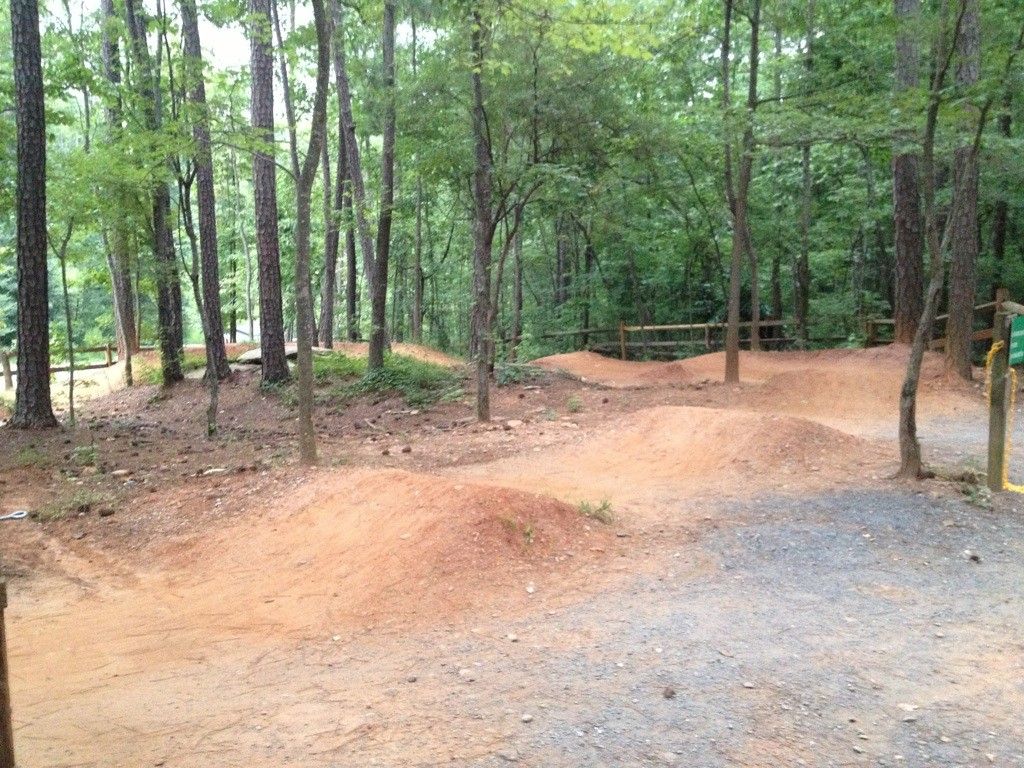 Dirt bike jumps and mounds in a wooded area with green trees. - Big Creek Greenway Trailhead loop from Big Creek Trailhead