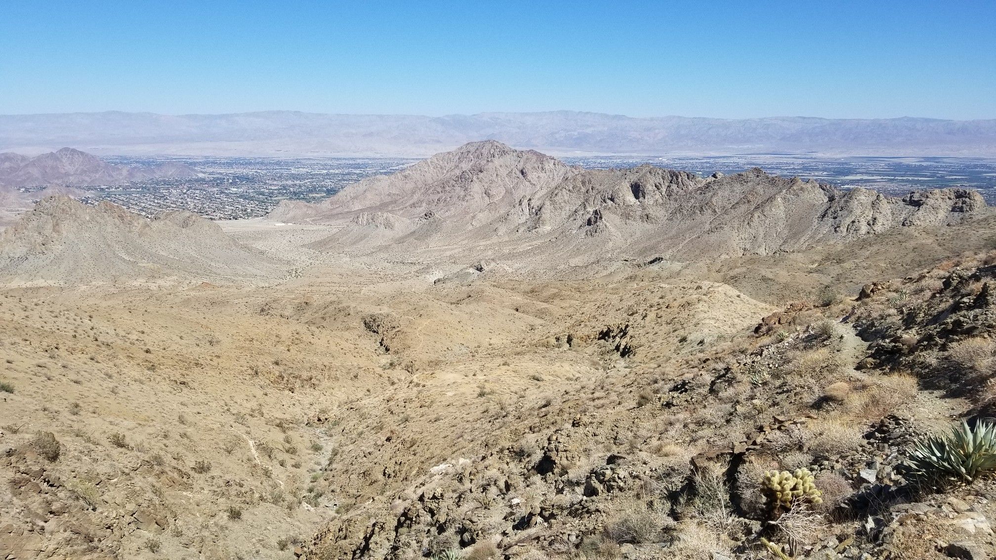 Vast desert mountain landscape with a distant town under a clear blue sky. - Boo Hoff Trail