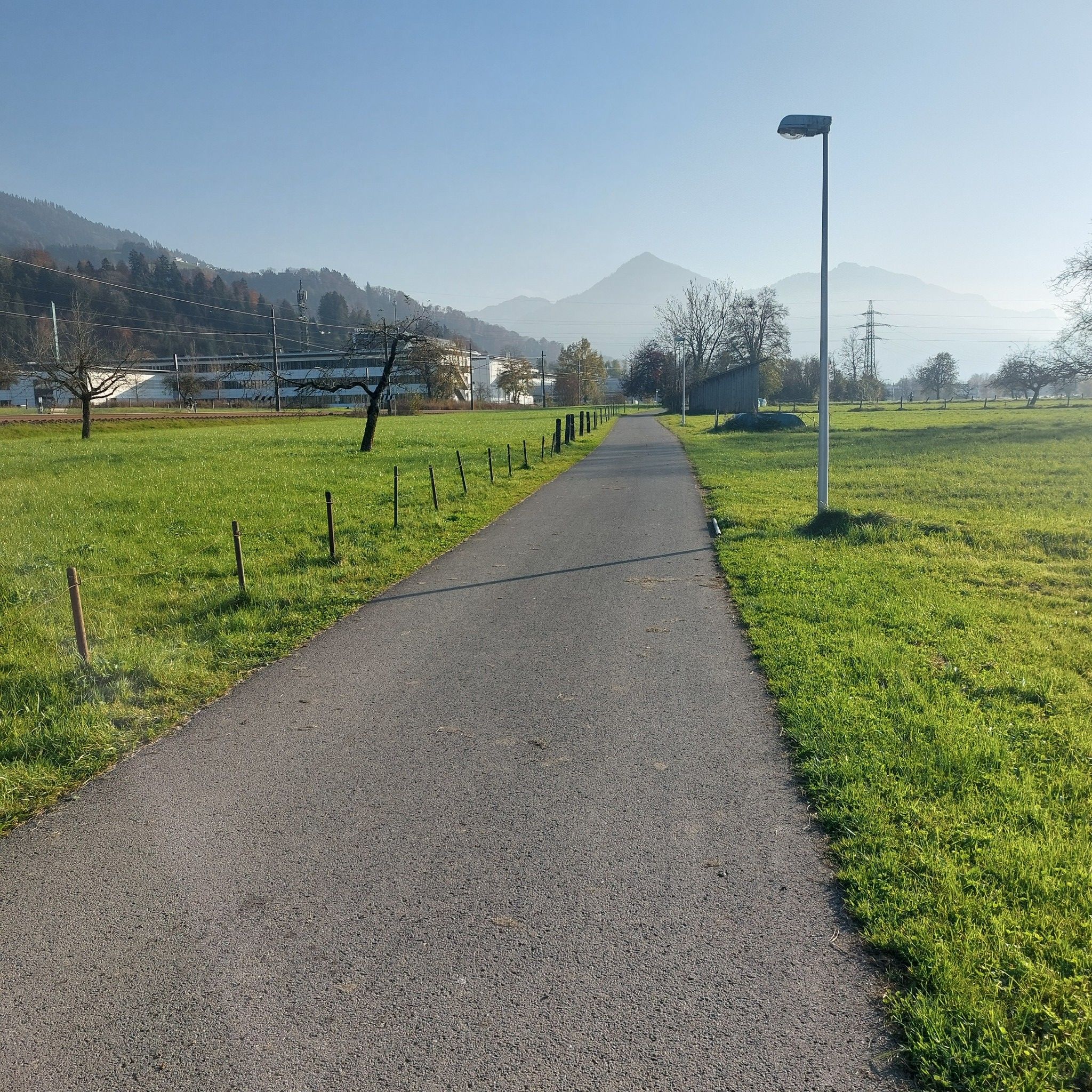 Asphaltweg durch Wiesen, paralelle zum Bahngleis