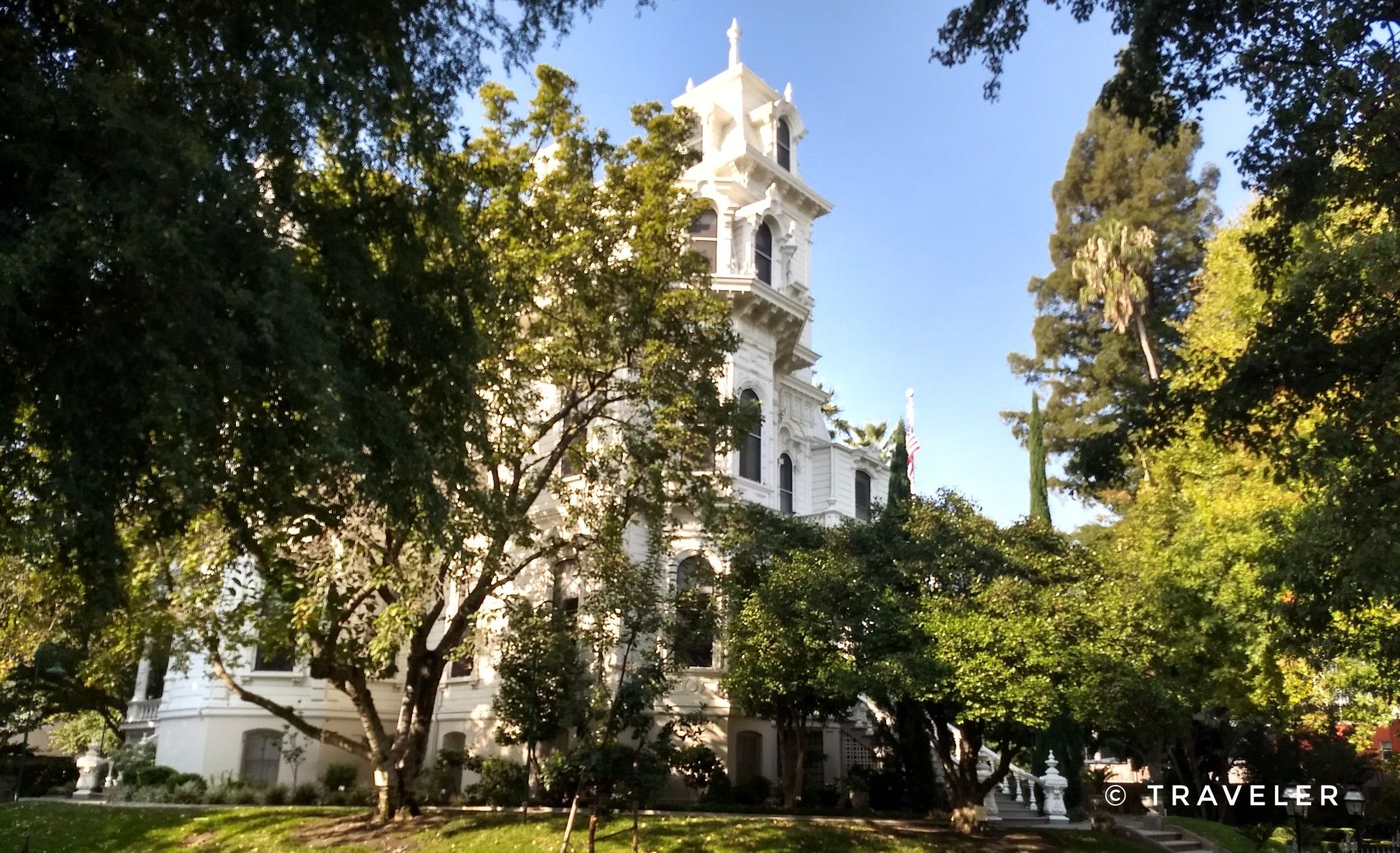 Ornate white building with a tower, framed by lush green trees. - Old Sacramento via Downtown Sacramento loop