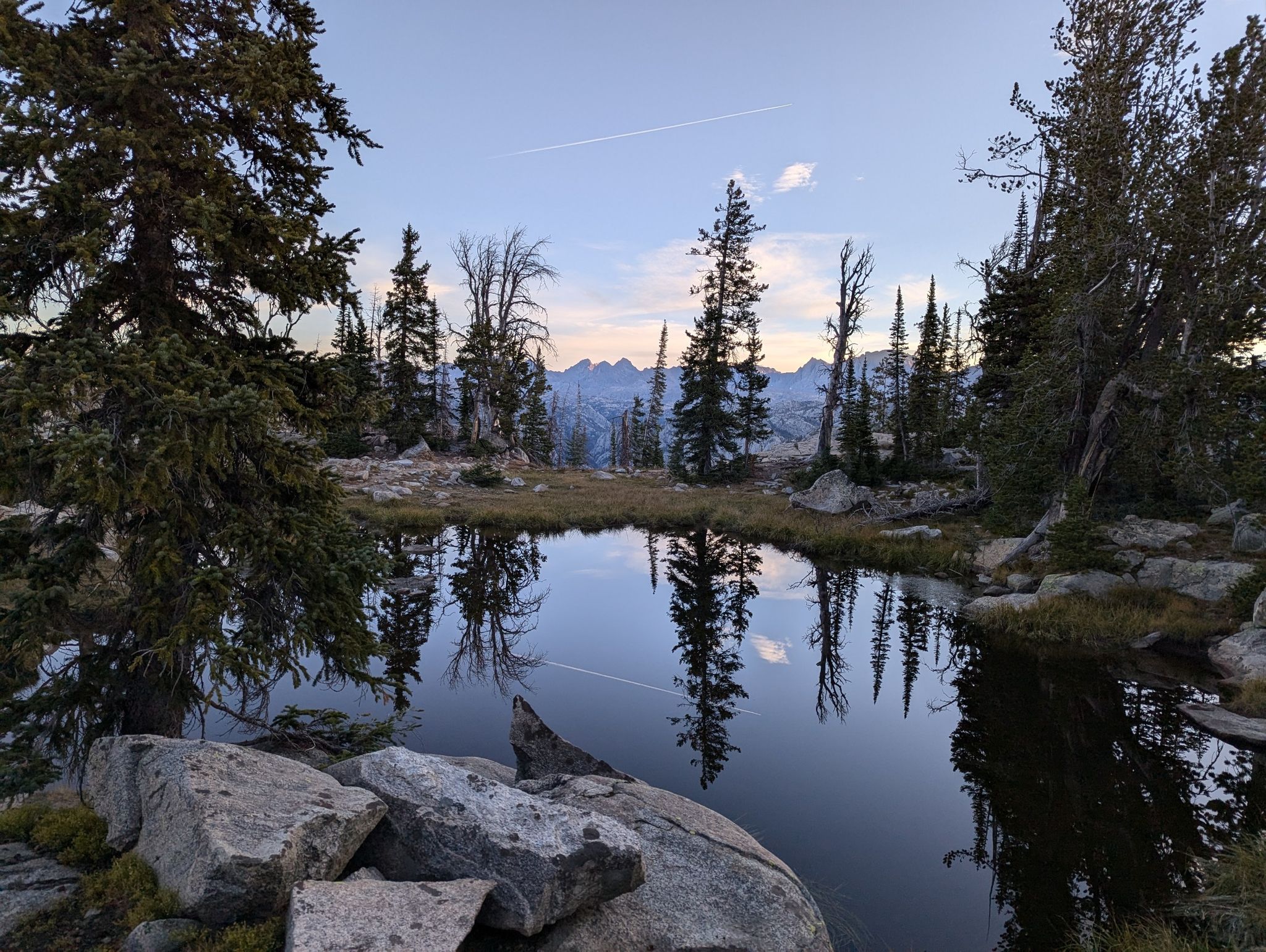 Serene mountain lake reflecting pine trees under a soft, clear sky. - Photographers Point via Pole Creek Trail