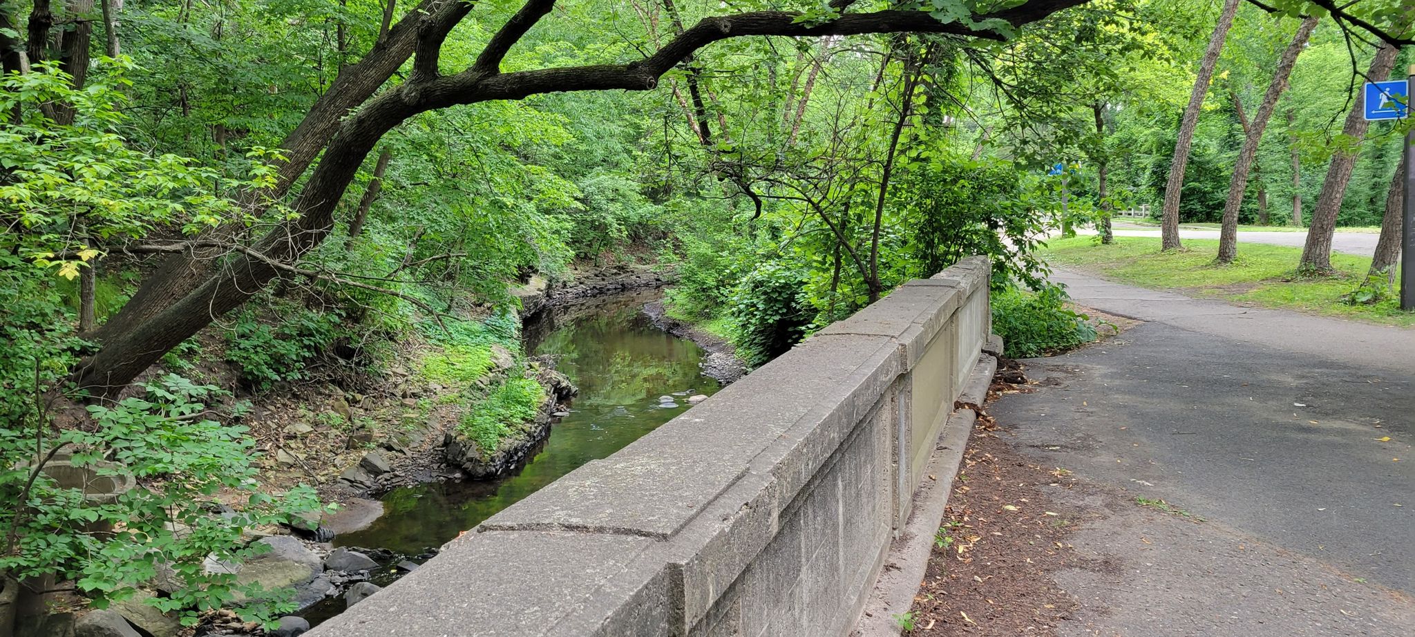 A concrete bridge spans a small stream next to a paved path. - Minnehaha Creek Trail: Tangletown Section