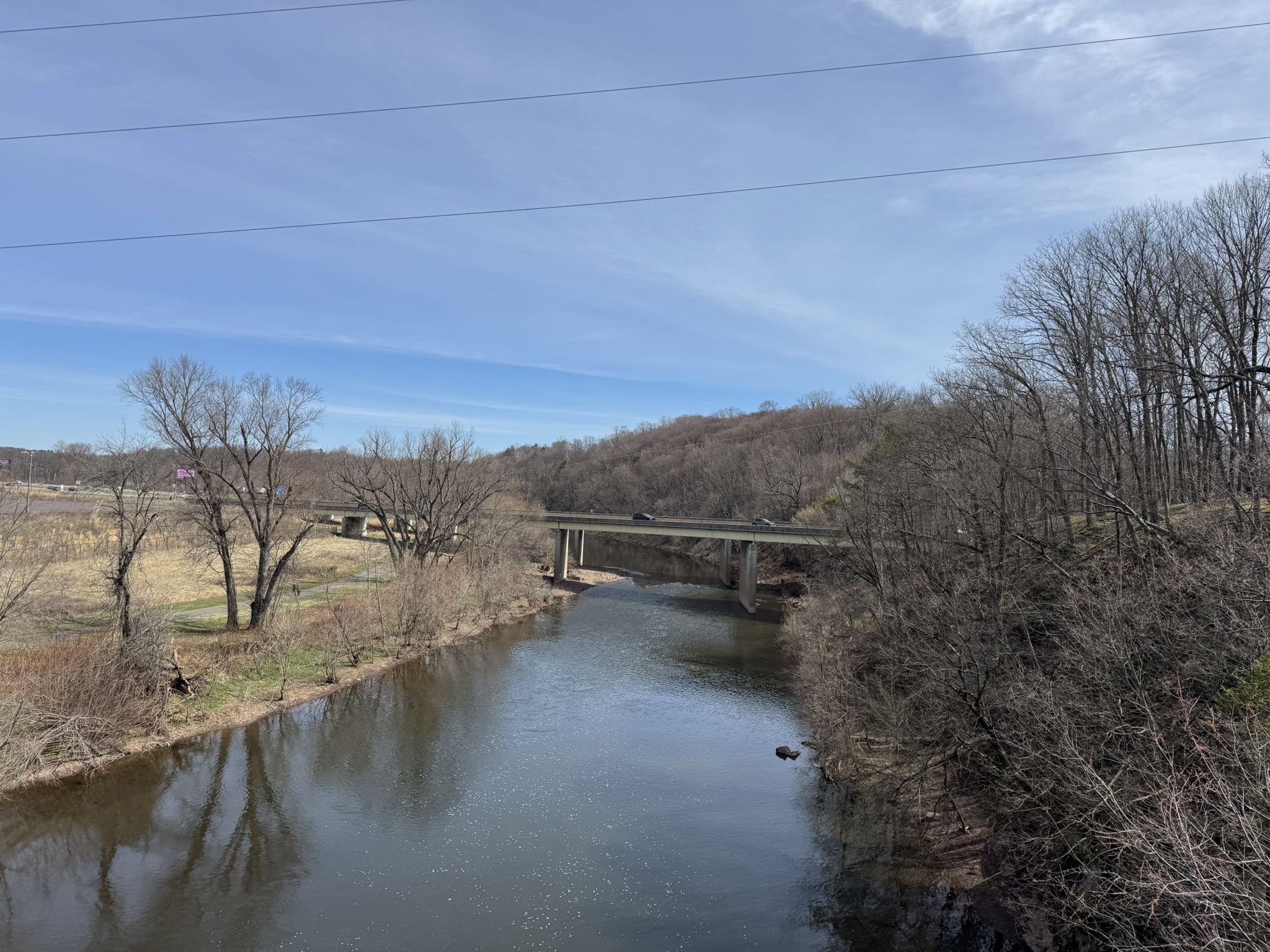 Wide river flowing under a bridge, with bare trees and distant hills. - View from Sullivan's Bridge – Schuylkill River Trail loop from Elm Street