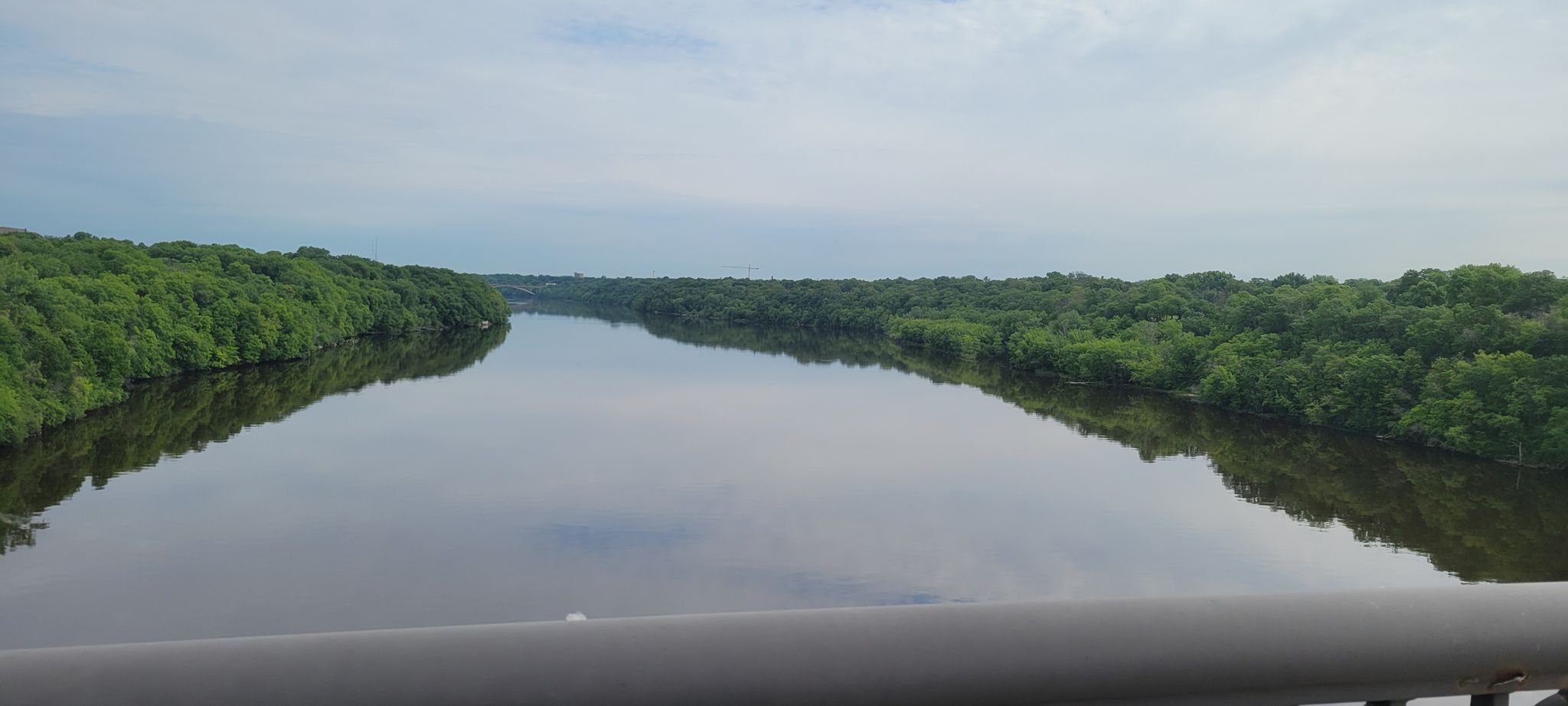 Wide river reflecting an overcast sky, flanked by dense green trees. - Lake Nokomis – Lake Nokomis Pathway loop from Lake Street/Midtown
