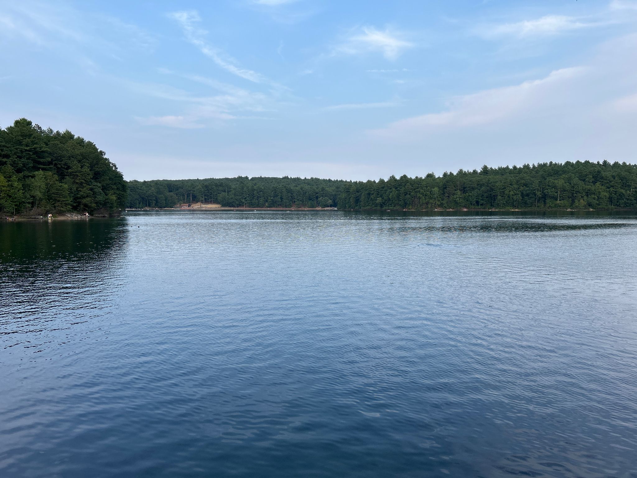 Calm lake surrounded by green forests under a partly cloudy sky. - Ice Fort Cove — Walden Pond – Thoreau Cove & Cabin loop from Walden Pond