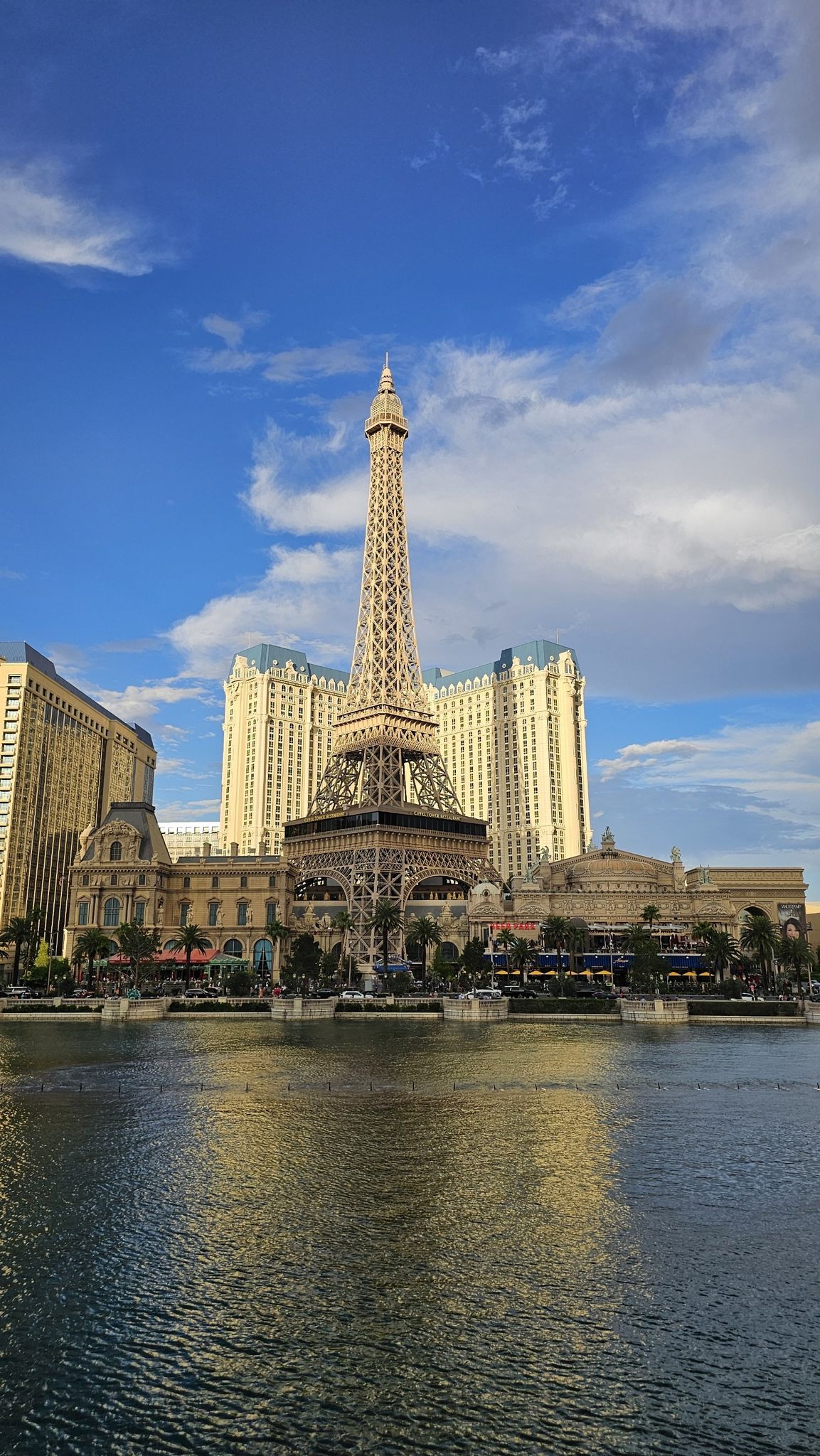 A tall tower replica stands by a lake with large buildings under a blue sky. - Central to Southern Strip loop (The Venetian to the Luxor)