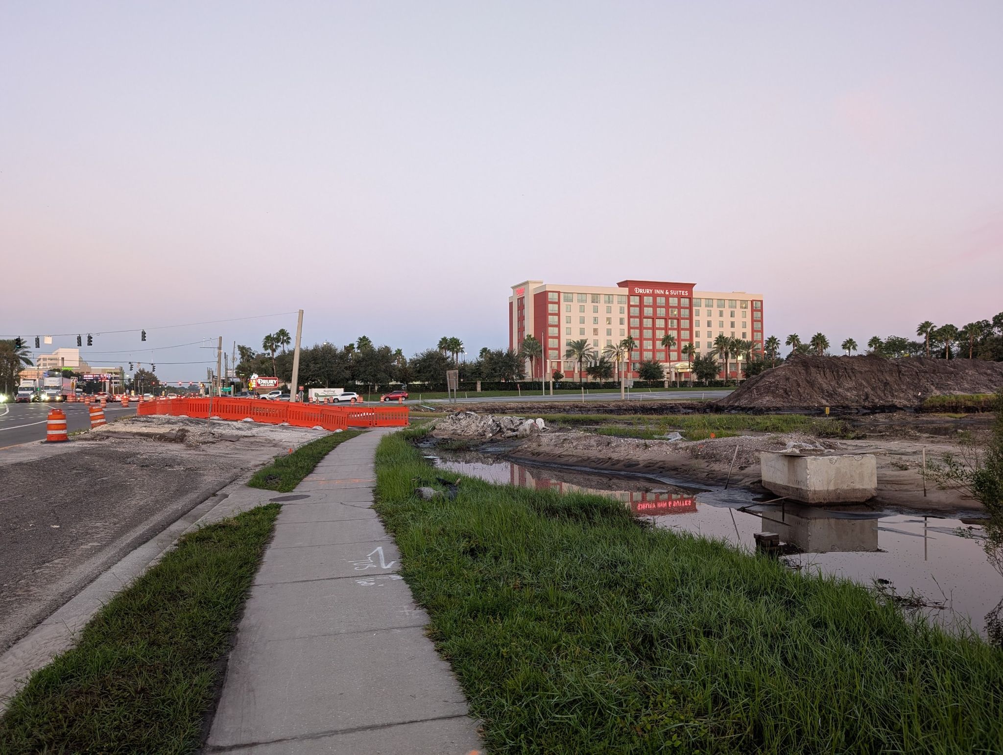 Urban construction site with a large hotel building under a soft, pink sky. - Orange County Convention Center loop from Spring Lake
