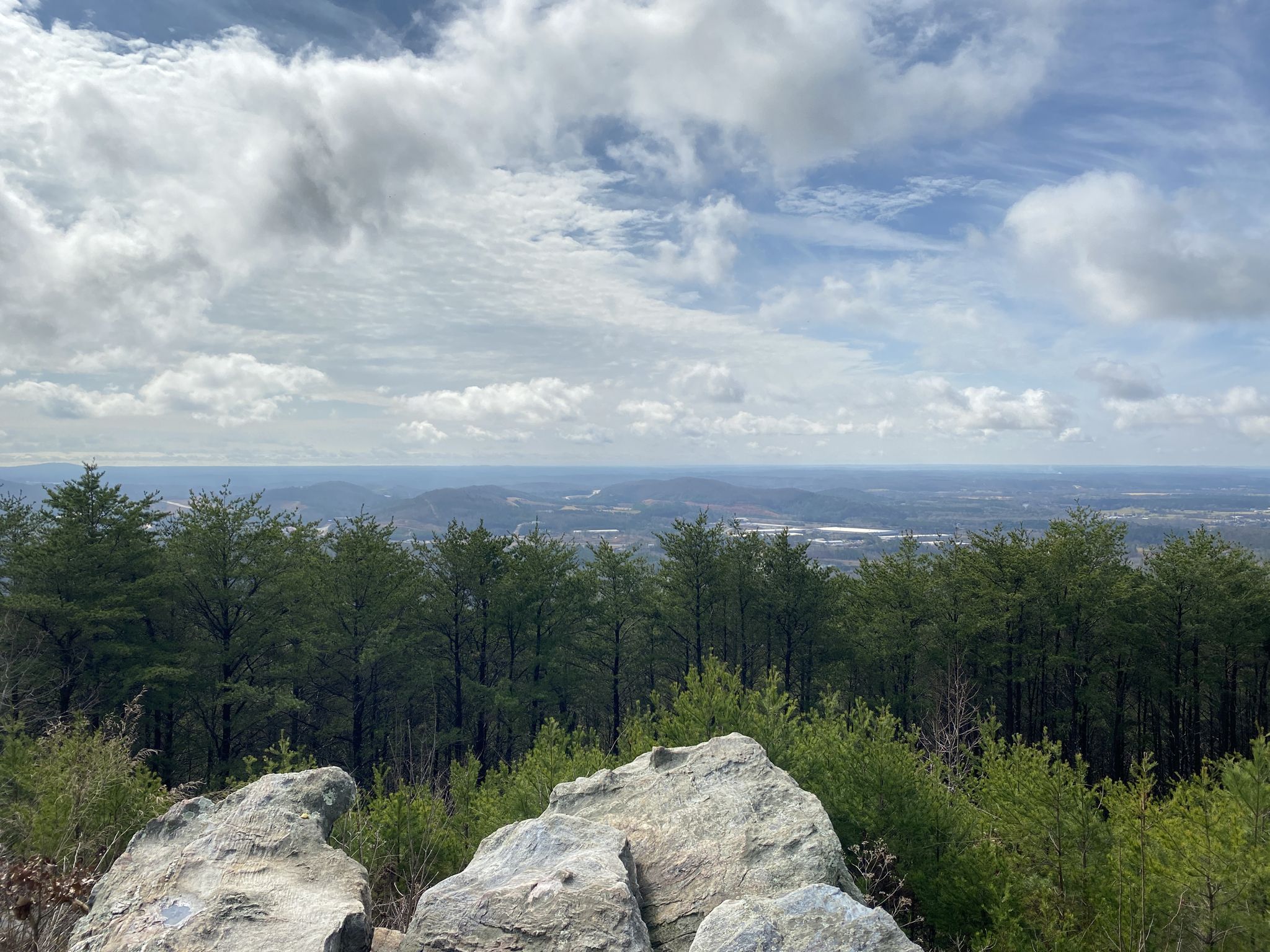 Bright mountain vista with distant valley, green trees, and foreground rocks. - Pine Mountain West Loop