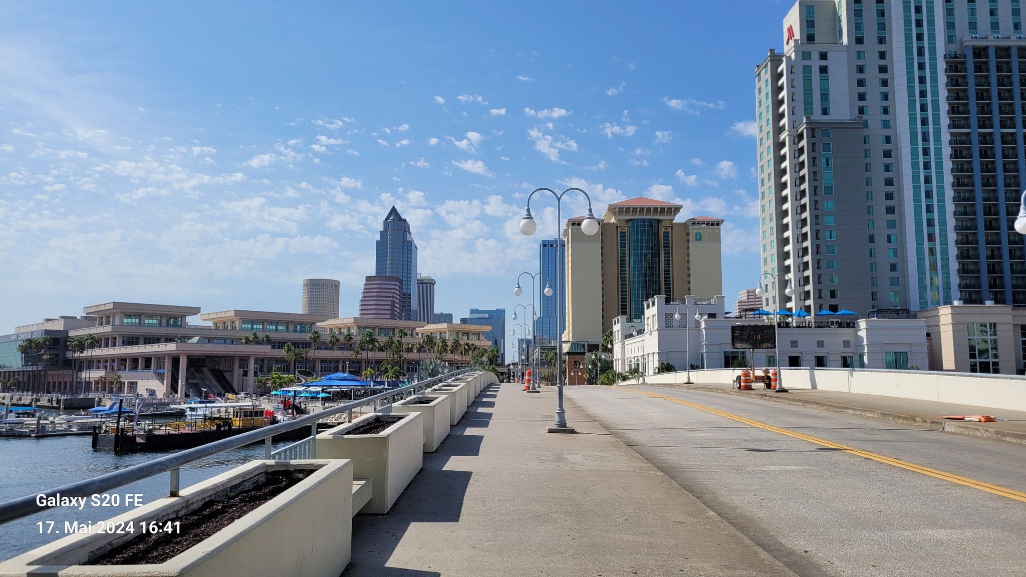 A bridge leads to a vibrant city skyline and waterfront on a sunny day. - Bayshore Linear Park loop from McKay Bay Nature Park