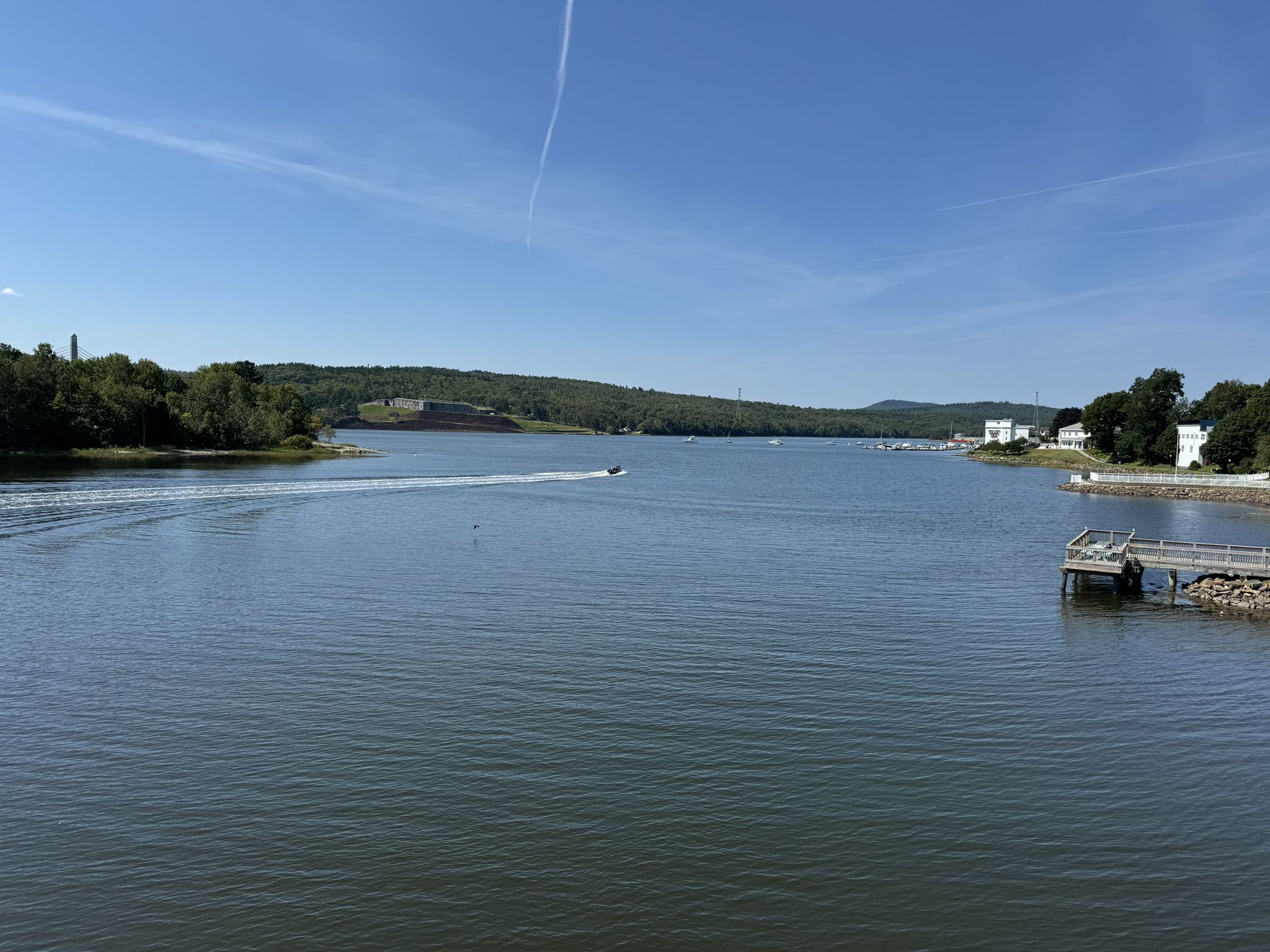 Wide river with a boat, tree-lined banks, and a dock on a sunny day. - Bucksport – Verona Island loop from Bucksport