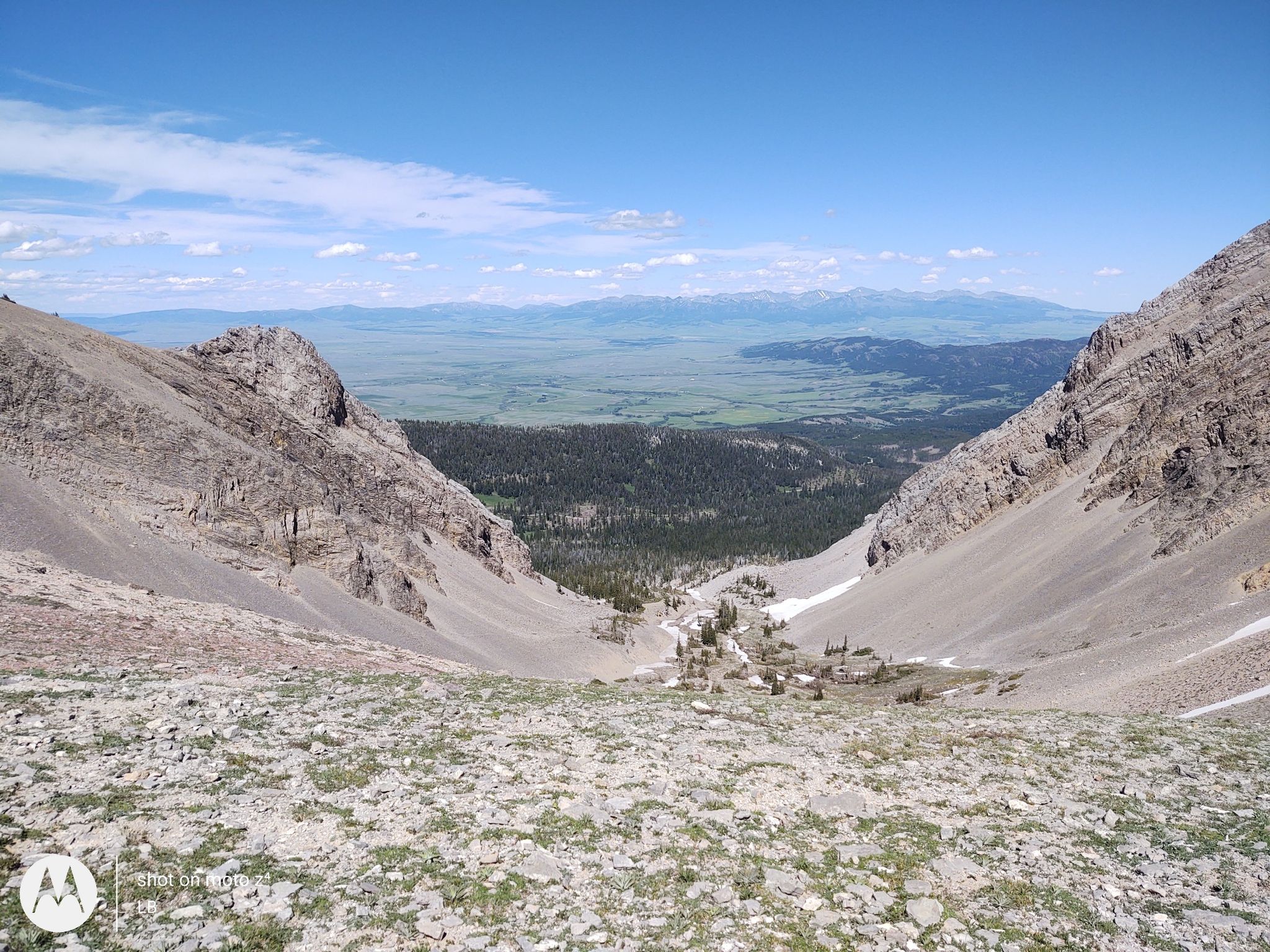 Wide view of a rocky mountain valley leading to green plains and distant peaks. - Sacagawea Peak via North Cottonwood Trail