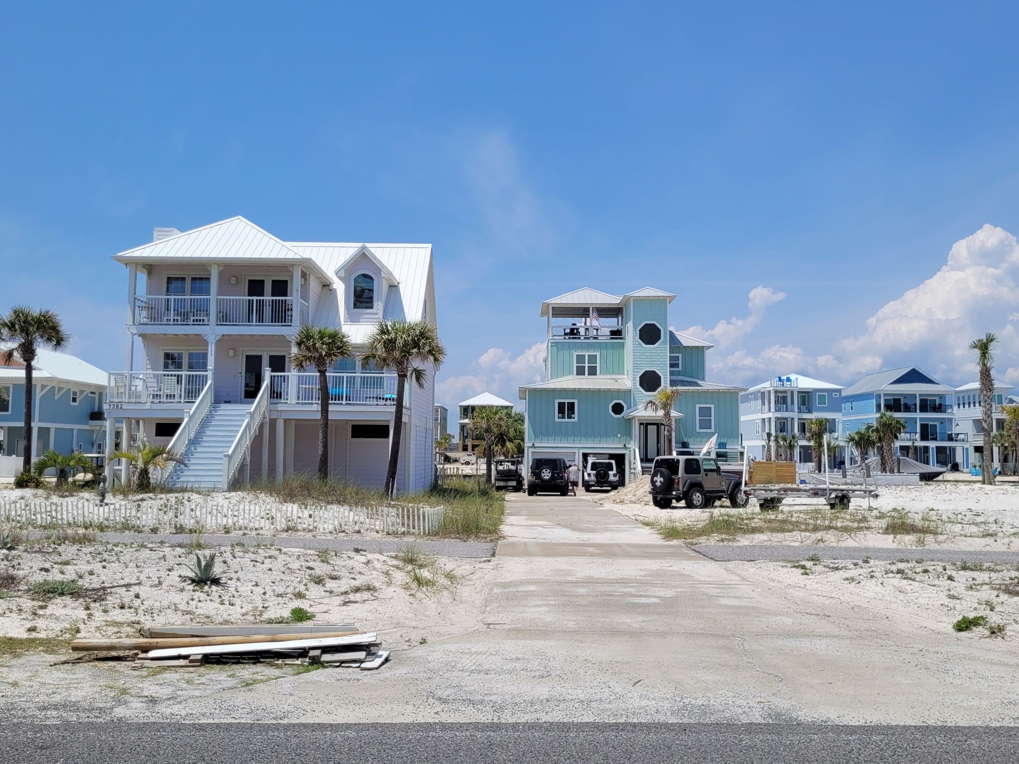 Brightly lit beach houses and vehicles on sandy ground under a clear sky. - Gulf Boulevard Trail – Navarre Beach loop from Public Beach Access #38C