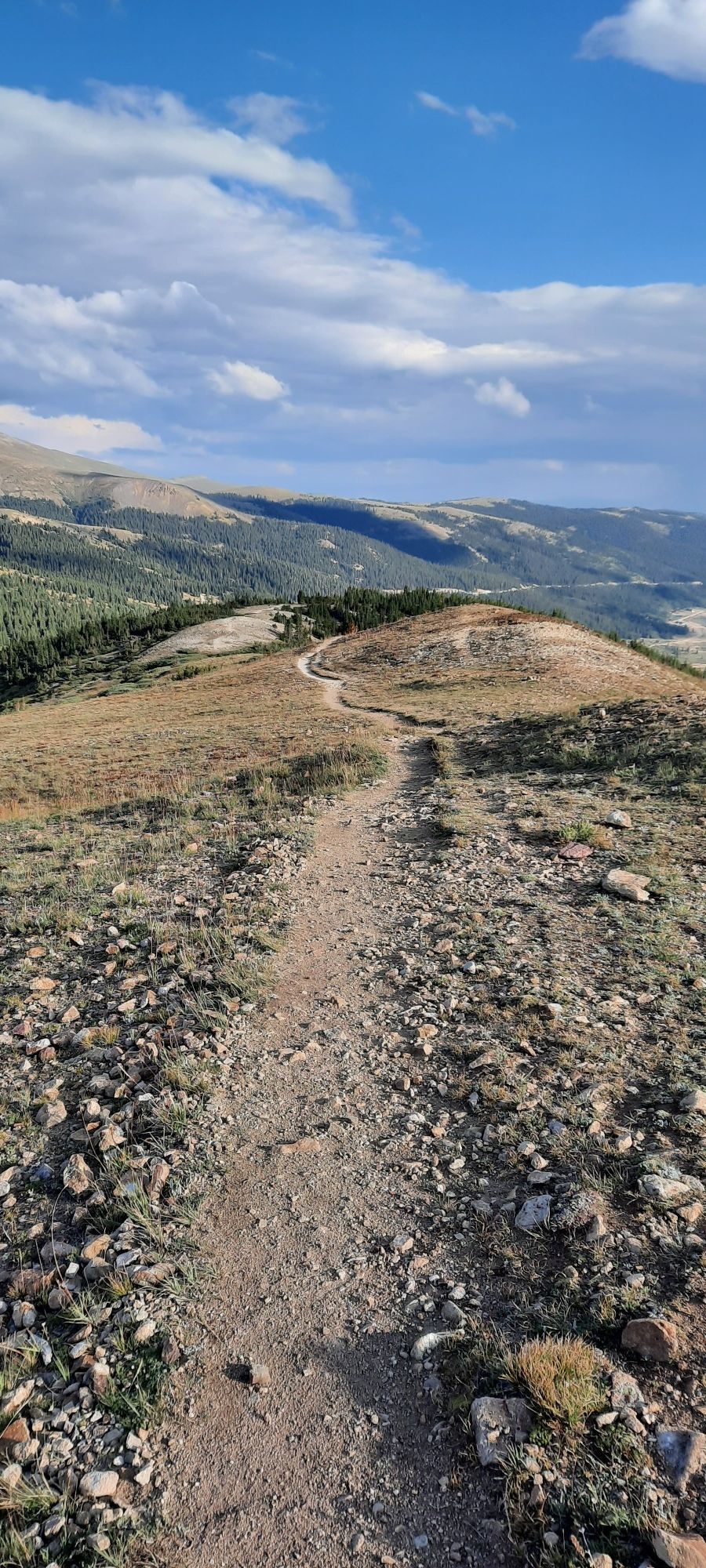 A winding dirt path leads over a rocky, barren mountain ridge. - Ling Road Loop