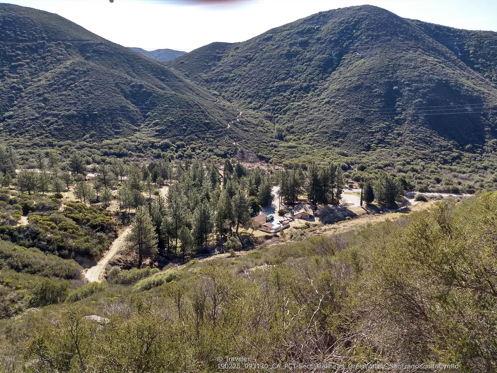 Lush green valley with pine trees and buildings nestled between steep hillsides. - Grass Mountain via San Francisquito Canyon Road