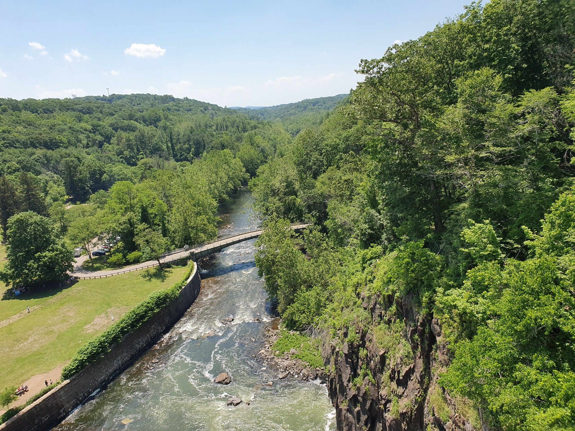 Aerial view of a river winding through a green valley with a bridge. - New Croton Reservoir Loop