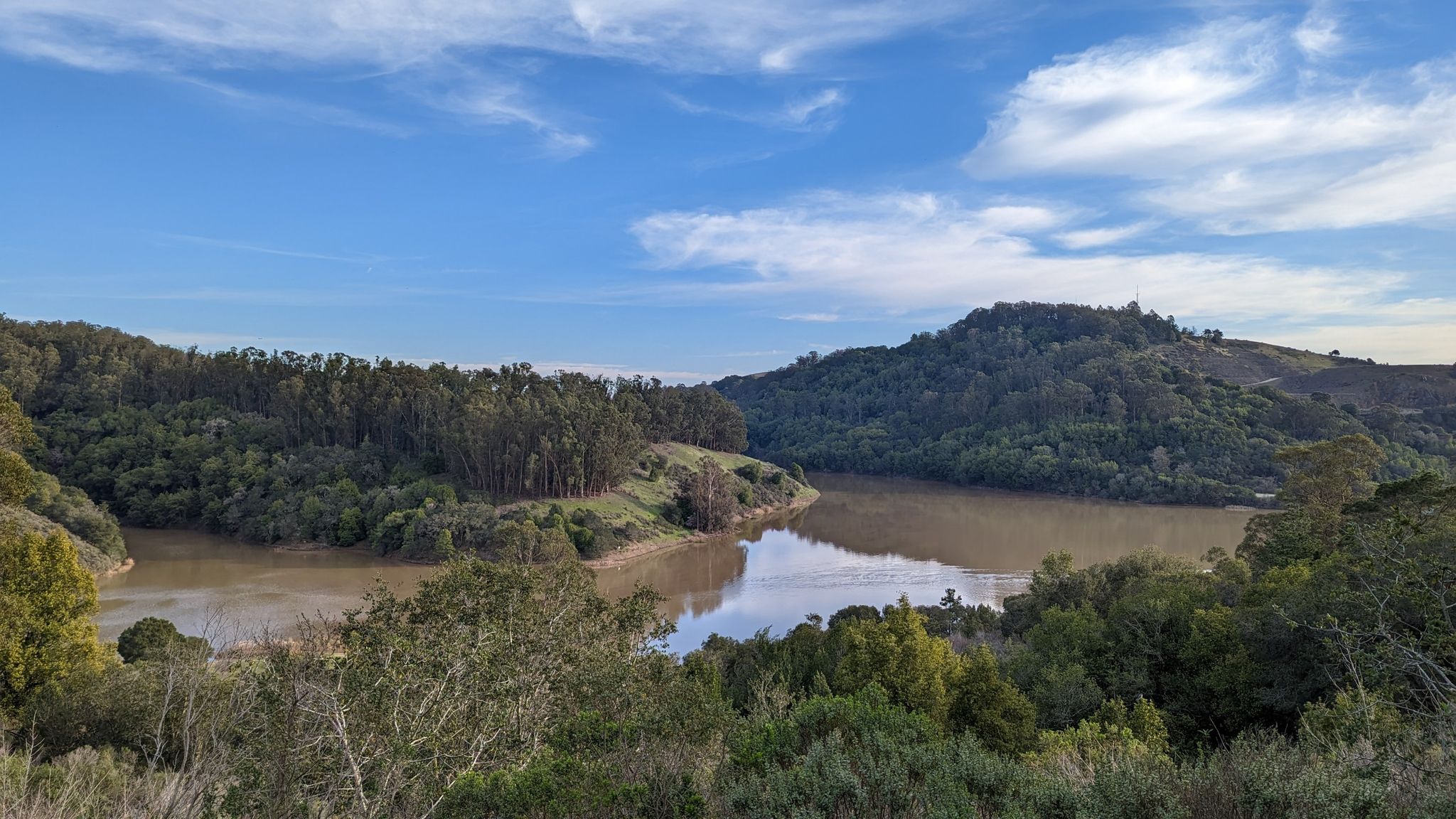 Lake surrounded by lush green hills under a bright blue sky with clouds. - Bass Cove and Goldenrod Trail Loop