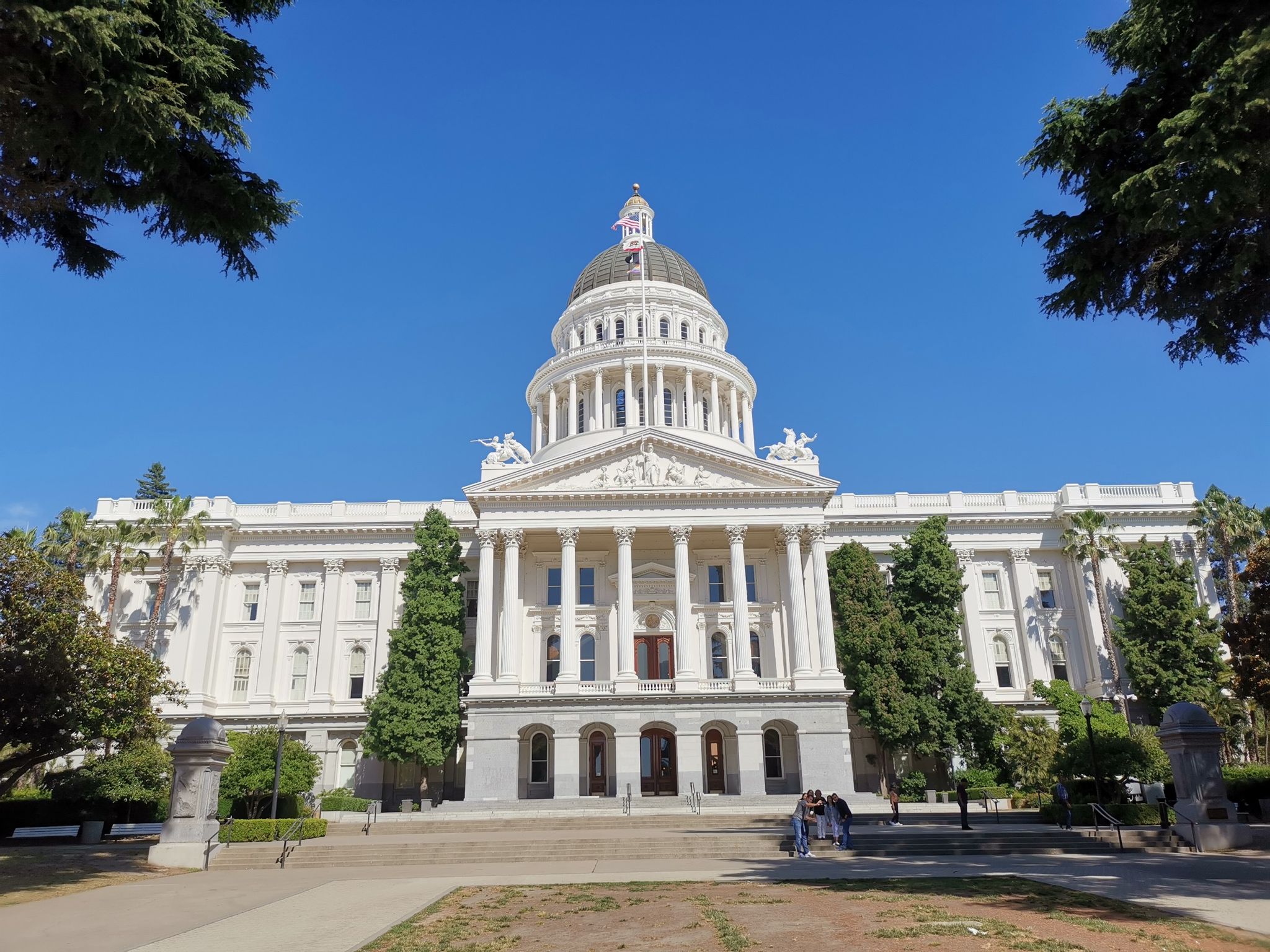 Grand white domed building with columns under a clear blue sky. - Capitol Park Loop Trail