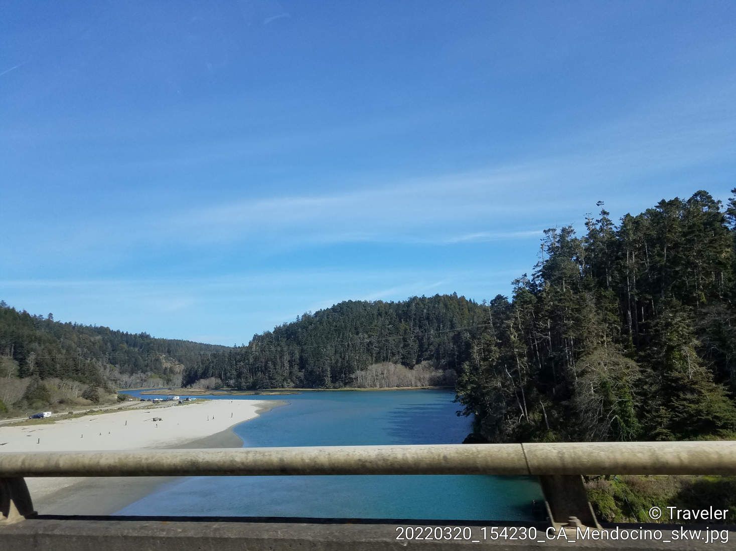 River with a wide sandy beach, bordered by dense forest under a clear sky. - Mendocino Bay Viewpoint – Big River loop from Hendy Woods State Park