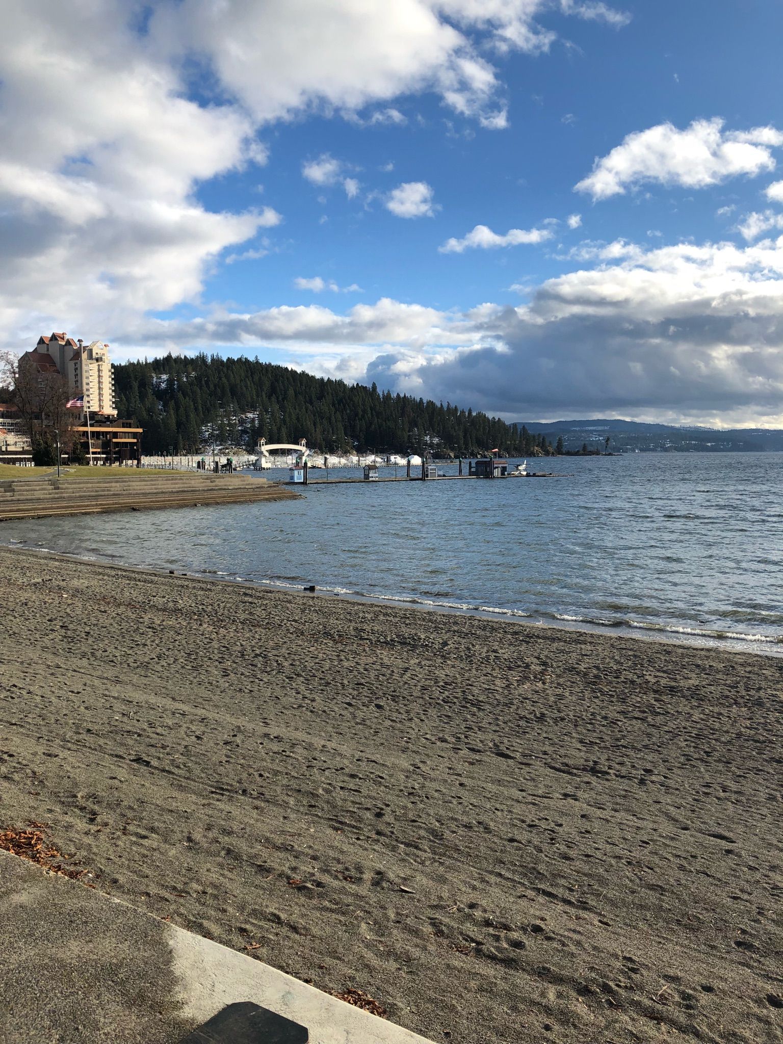 Wide sandy beach by a large lake with distant buildings and hills. - Silver Beach Marina loop from Coeur d'Alene