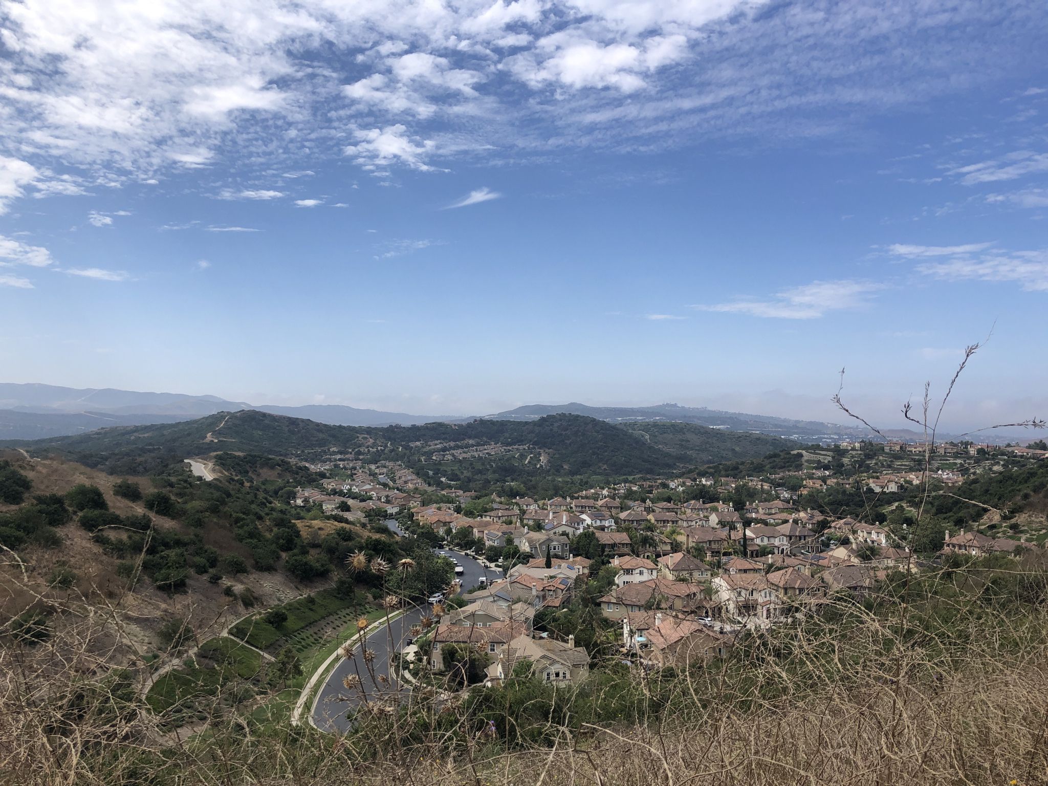 A panoramic view of a town nestled in a valley surrounded by hills. - Talega Loop