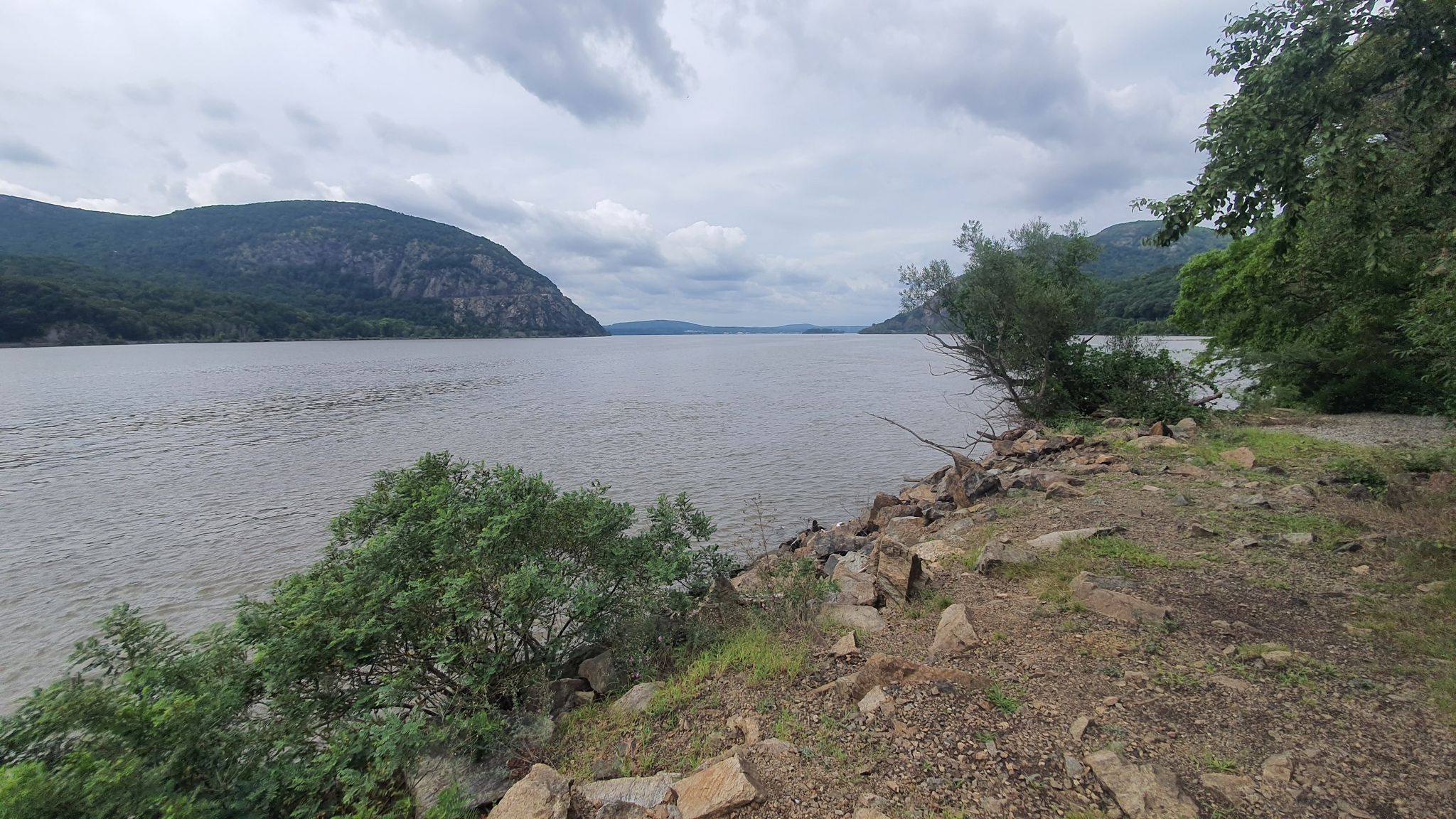Wide river between mountains under cloudy sky, with rocky, vegetated bank. - Nelsonville Trail – Parking spot loop from Cold Spring