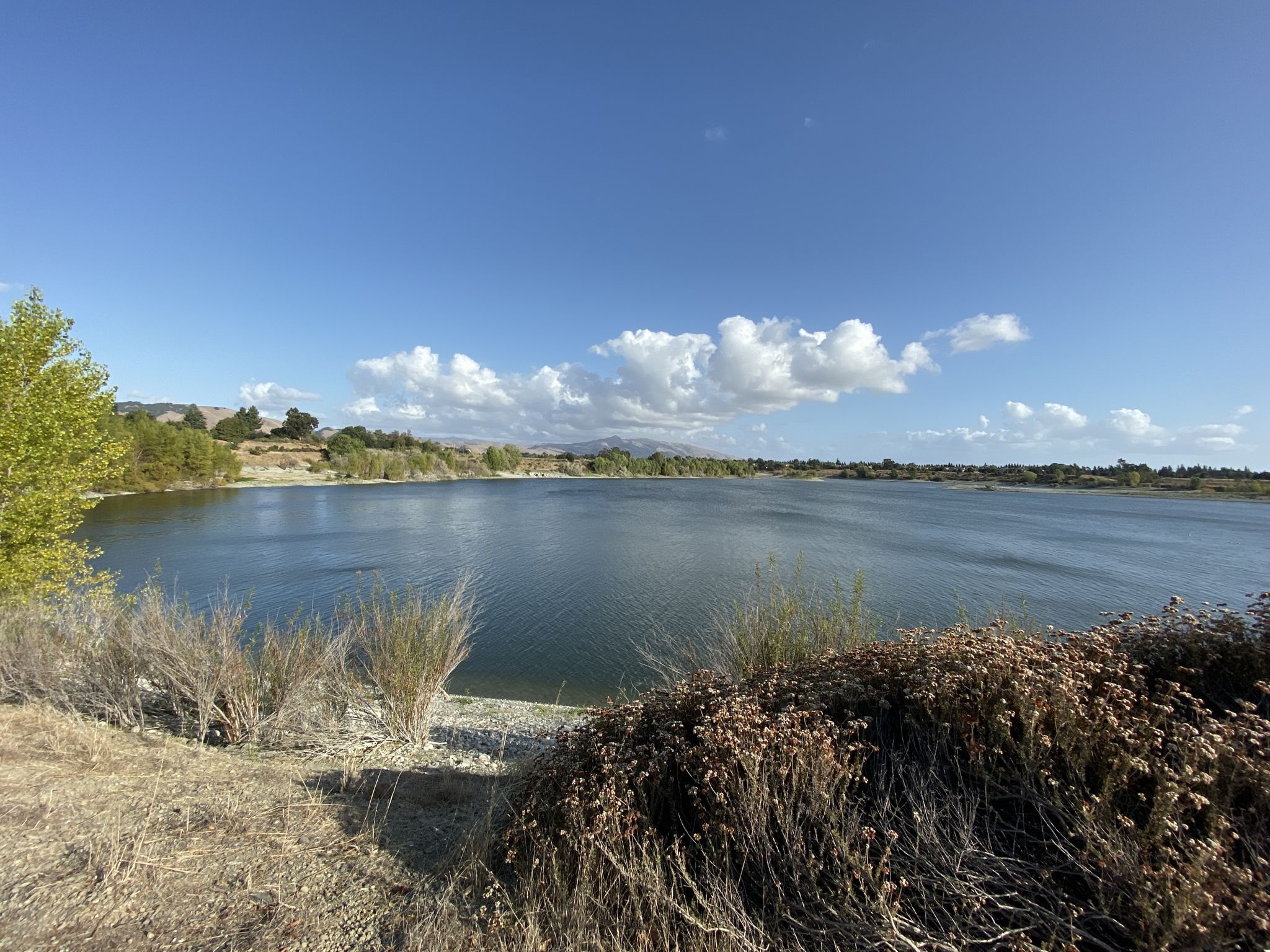 Expansive lake under a bright blue sky with scattered clouds. - Old Creek to Western Pacific Trail