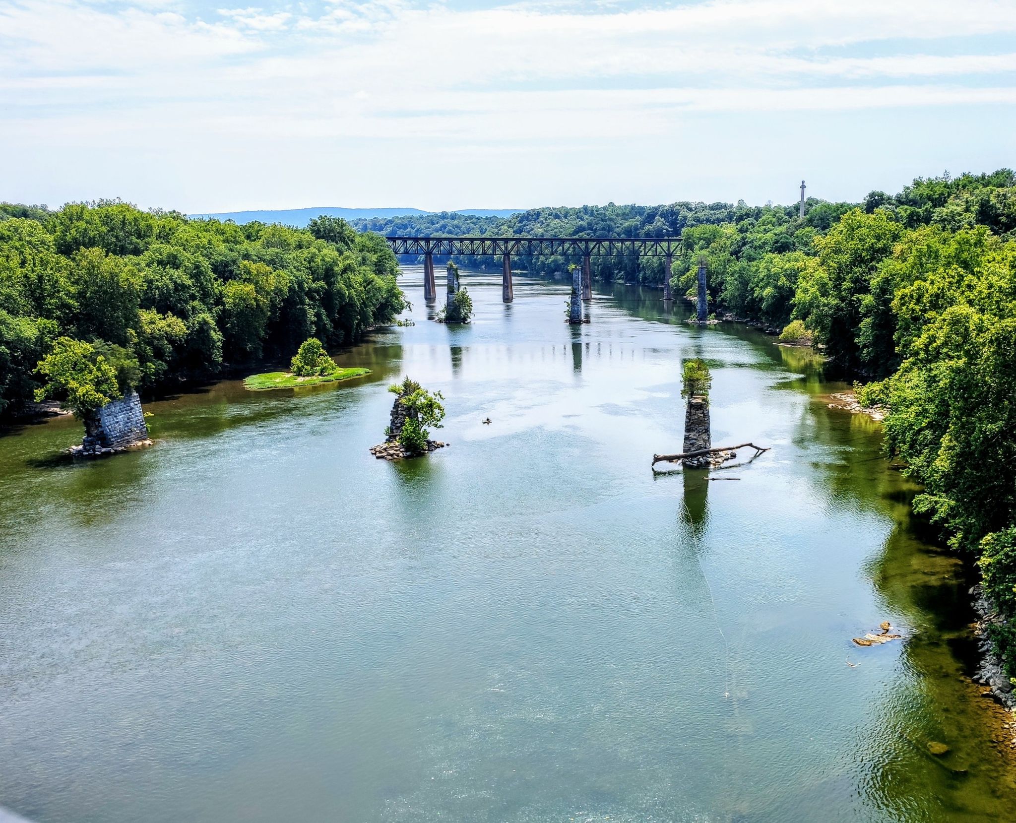Sunny view of a wide river with old bridge piers and a distant bridge. - Shepherdstown and Williamsport C&O Canal Loop