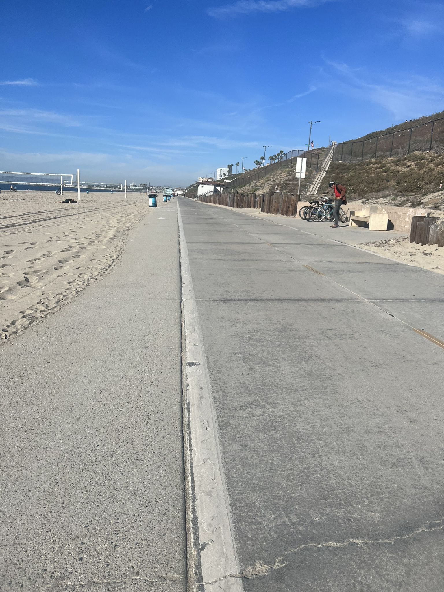 Concrete path next to a sandy beach with a volleyball net and distant hills. - Redondo Beach loop from Torrance