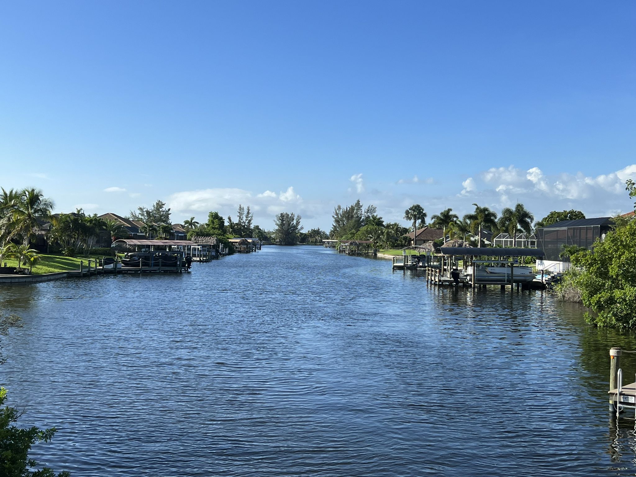 Wide canal lined with houses and boats under a bright blue sky. - Cape Coral loop