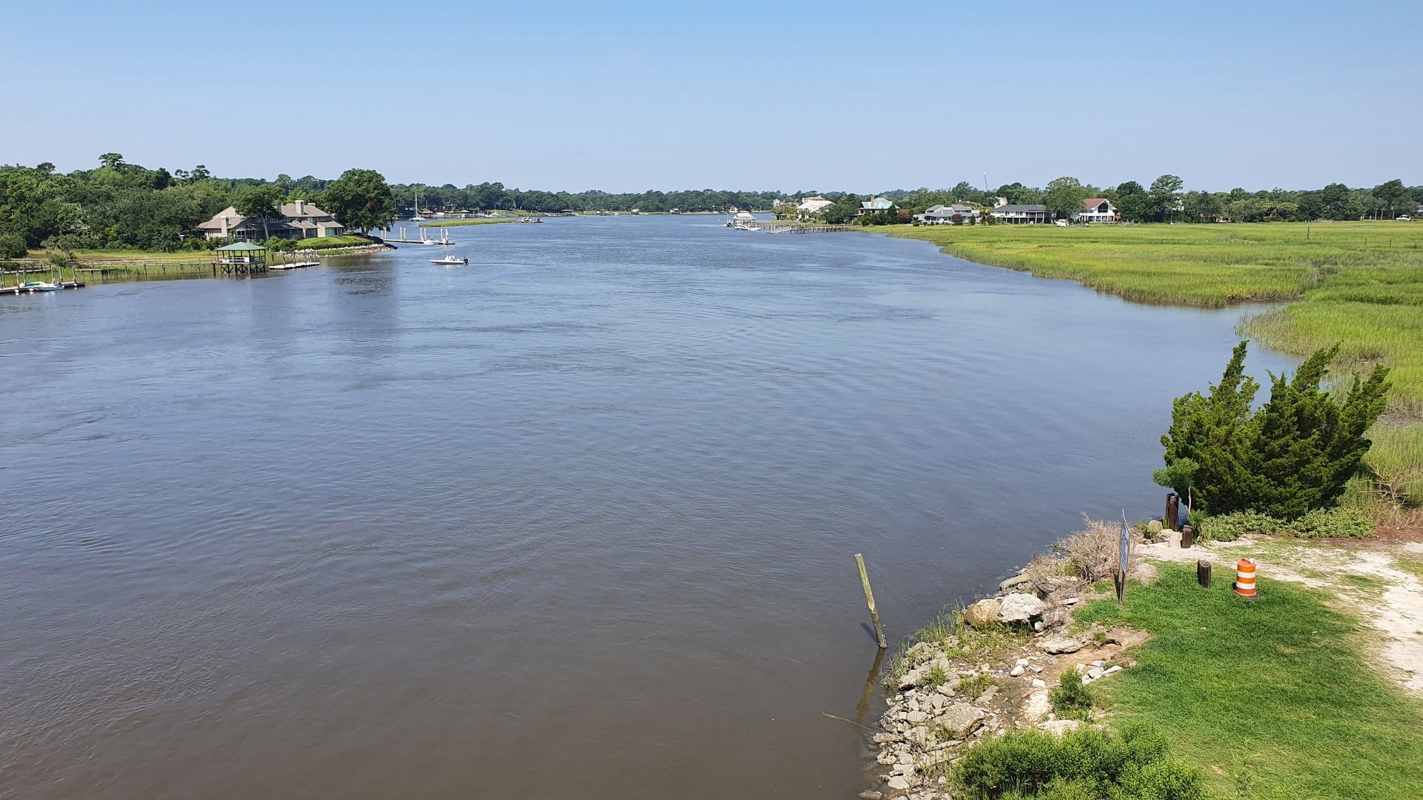 Wide river with boats, houses, and green marshland under a clear sky. - Stono River loop