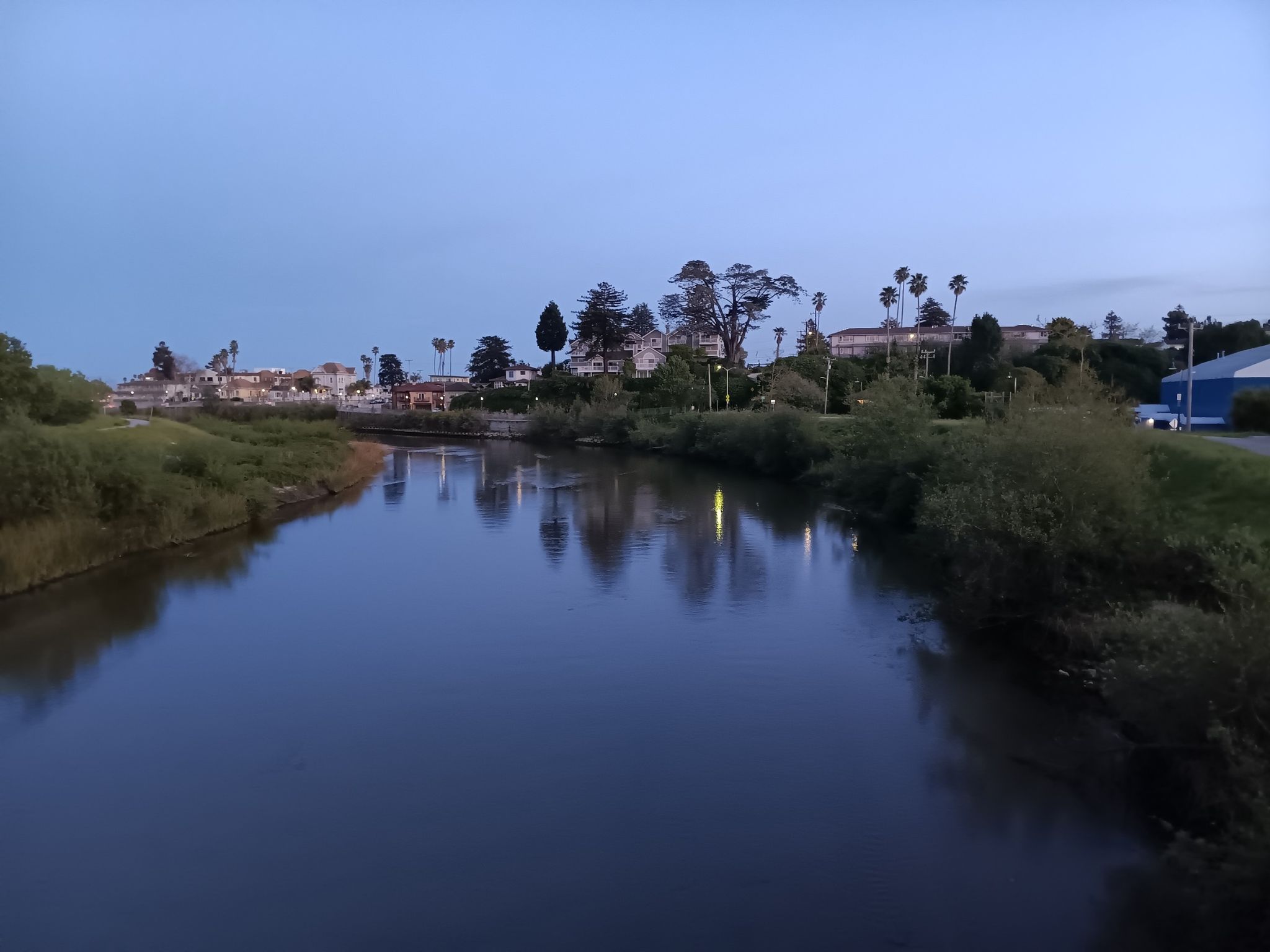A calm river reflects the soft blue light of dusk, with distant town. - Wilder Ranch Bike Path – Wilder Dairy Cultural Preserve loop from Boulder Creek