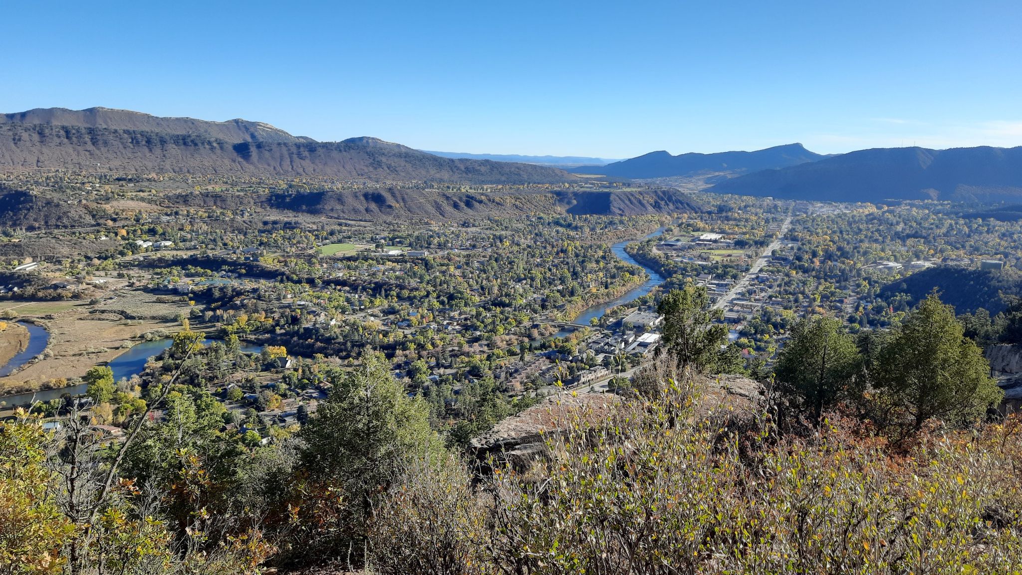 Expansive view of a valley, river, and town surrounded by mountains. - Animas Mountain Loop