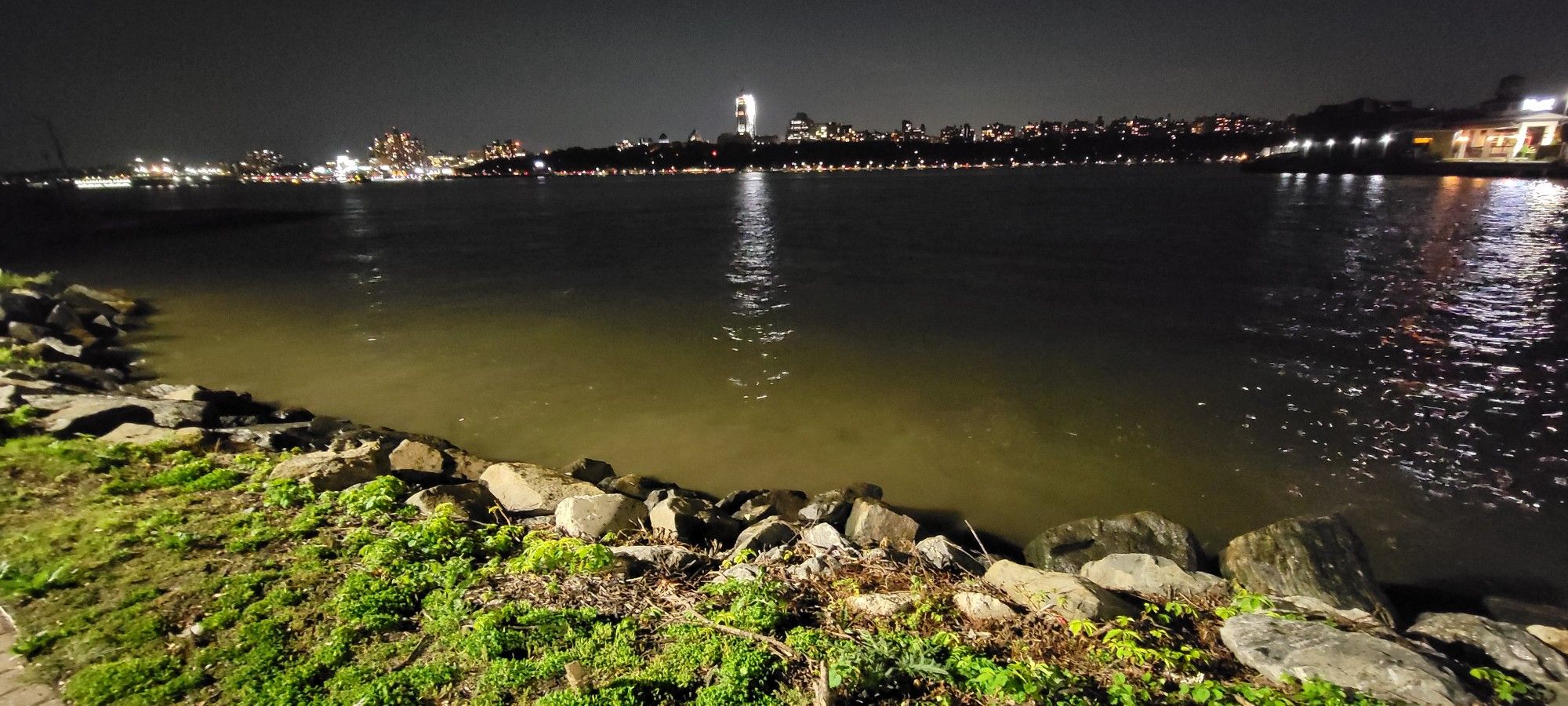 Nighttime river view with distant city lights reflecting on dark water. - Hudson River Waterfront Walkway: Edgewater