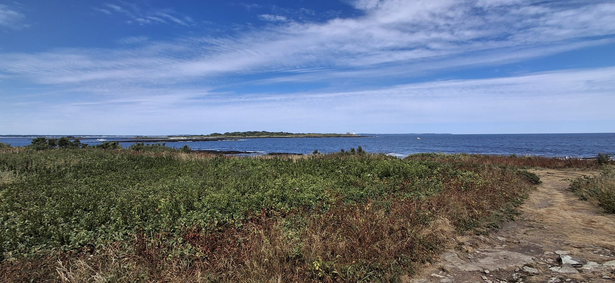Panoramic view of a blue ocean and distant land under a bright sky. - East Point Audubon Sanctuary Trail