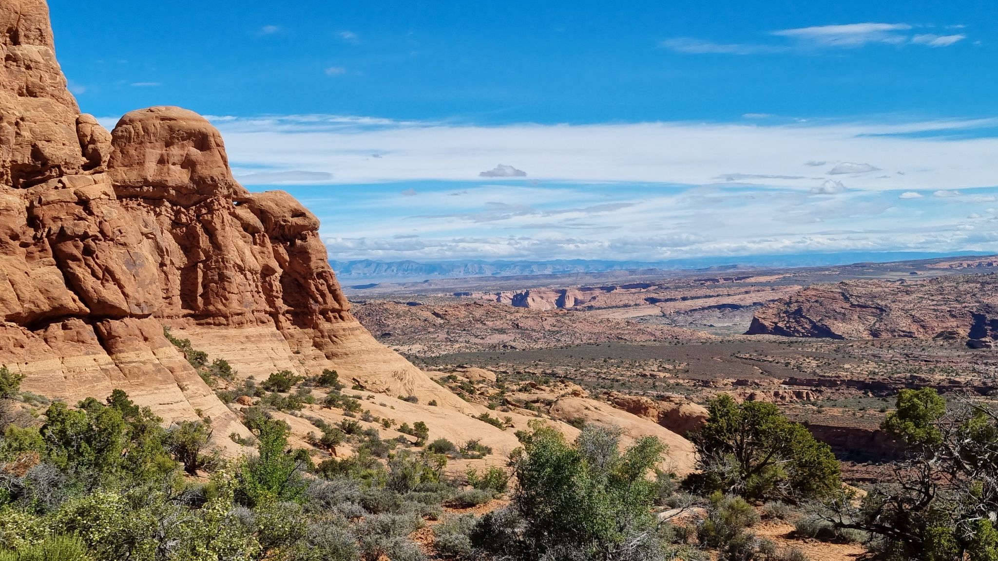 Red rock formations overlooking a wide desert vista under a blue sky. - Windows Sand Loop Trail