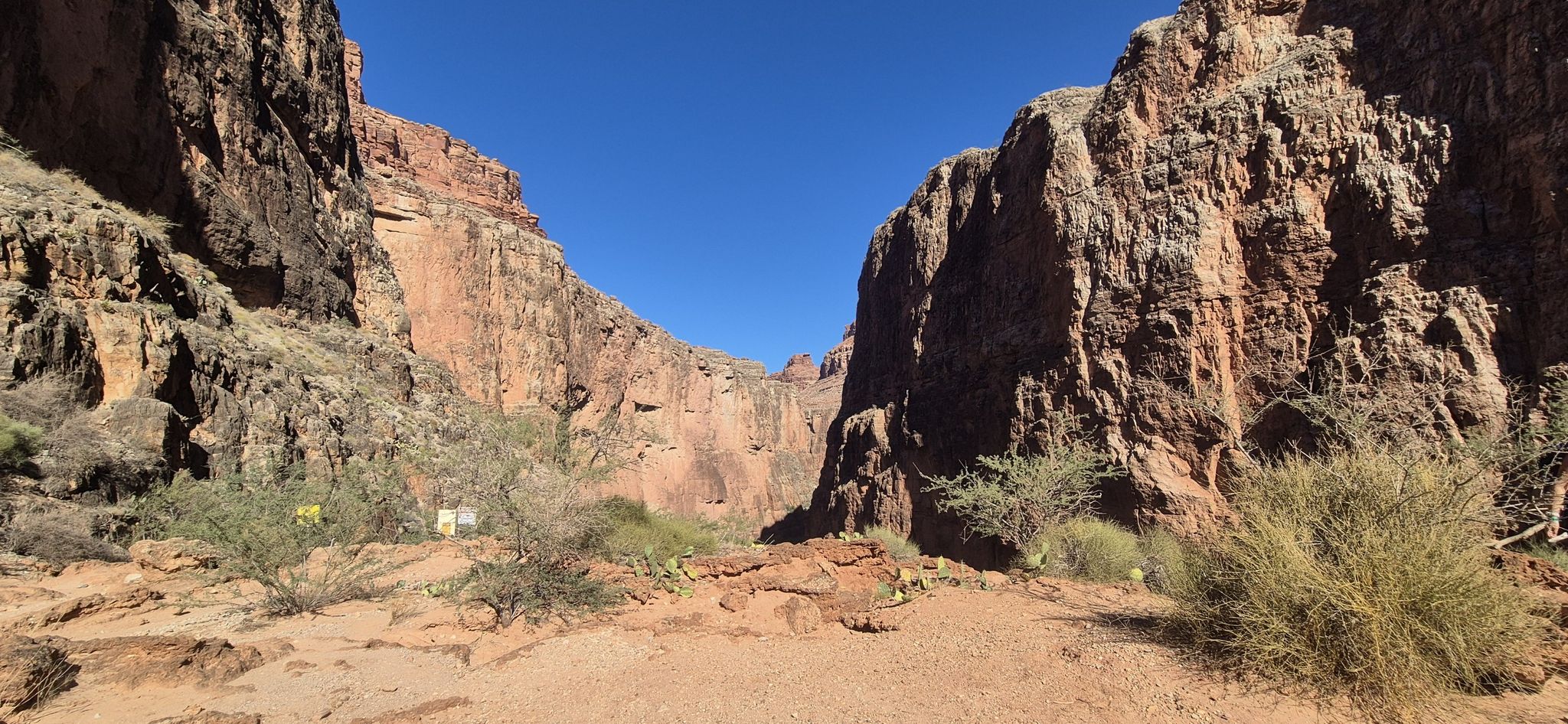 Deep canyon with towering red rock walls under a clear blue sky. - Mooney Falls loop from Havasu Falls