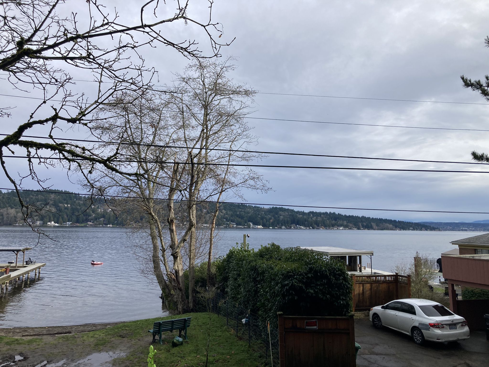 Cloudy lake view with bare trees, a dock, and a white car. - Floodwater reservoir loop from Kenmore