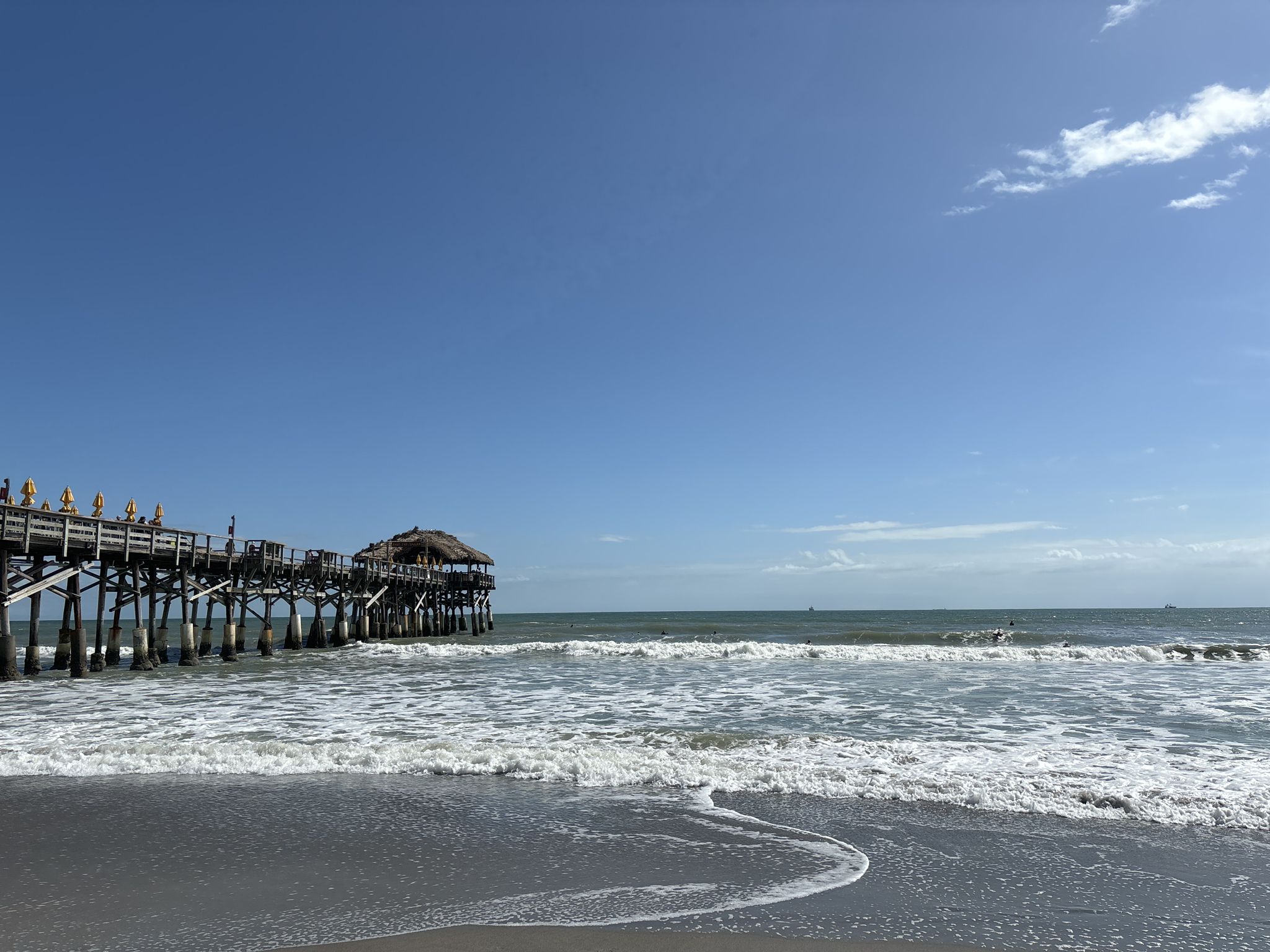 Pier over ocean with breaking waves and a clear blue sky. - Cocoa Beach Pier – Beautiful wooden boardwalk parallel to the sea loop from Hail Island