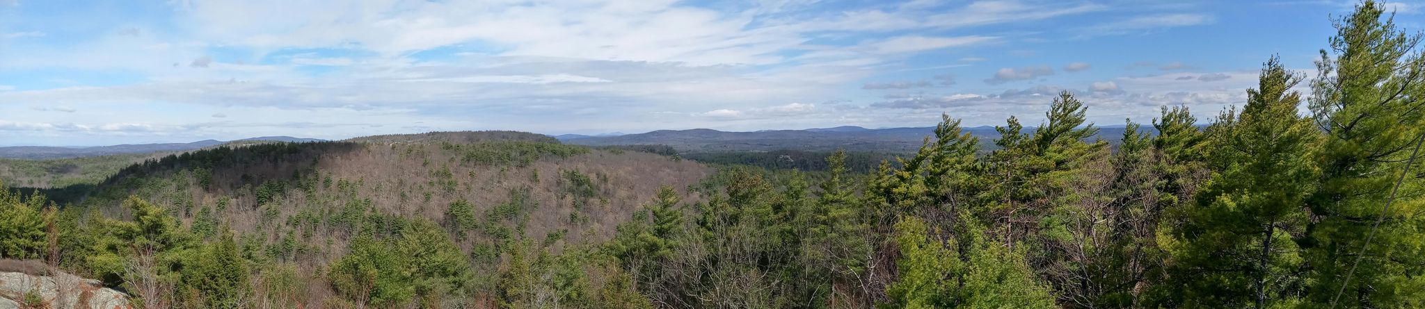 Expansive panoramic view of a forested mountain landscape under a partly cloudy sky. - Shaw Trail