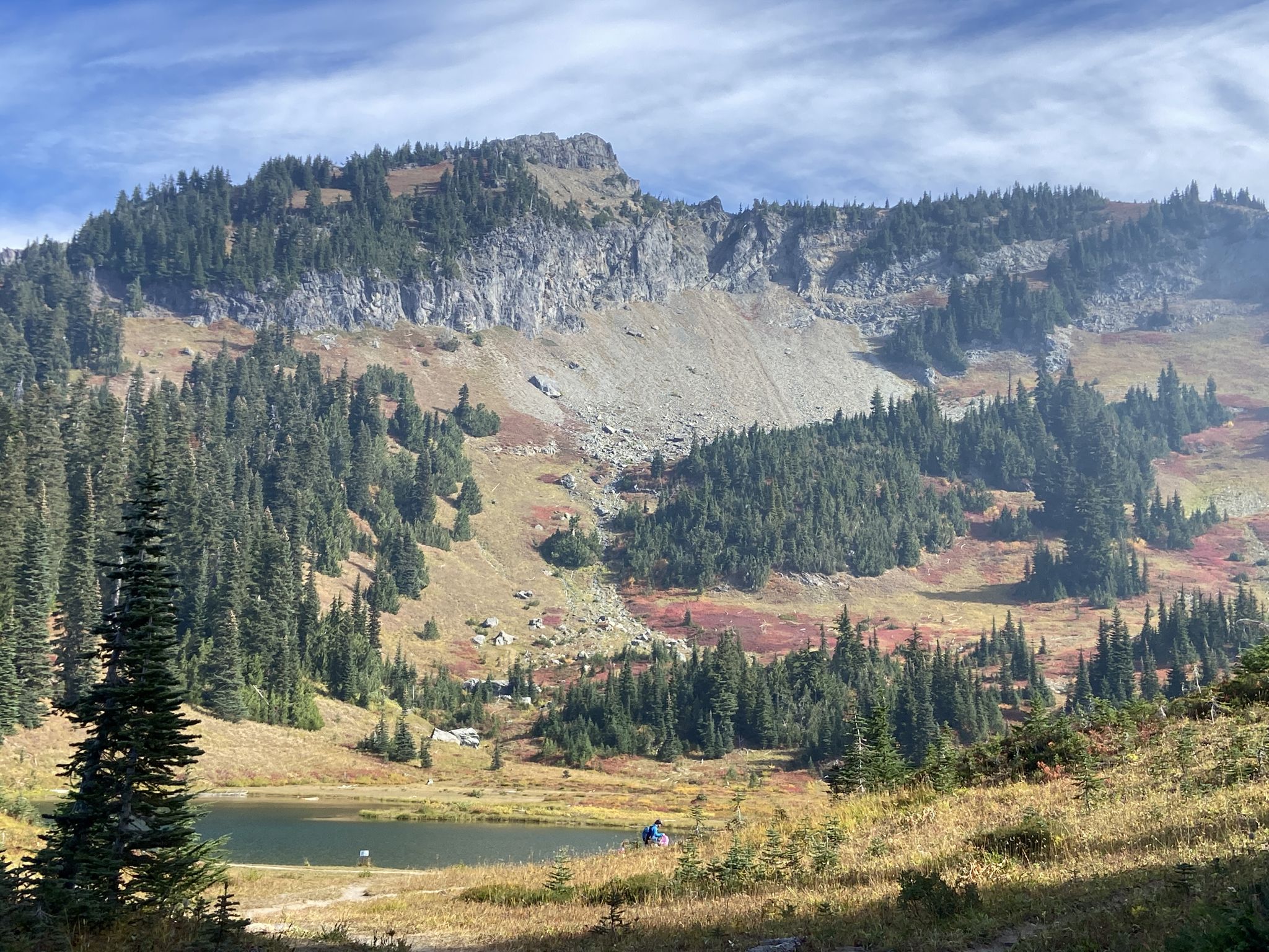 Mountain with rocky slopes, forest, and lake with colorful autumn foliage. - Tipsoo Lake – Chinook Pass loop from Corral Pass Road Trailhead