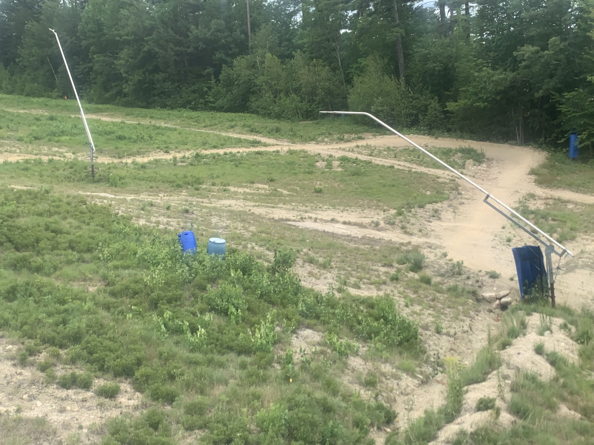 Grassy hillside with ski lift poles and dirt trails under diffused light. - Cranmore Mountain Bike Park loop from Redstone