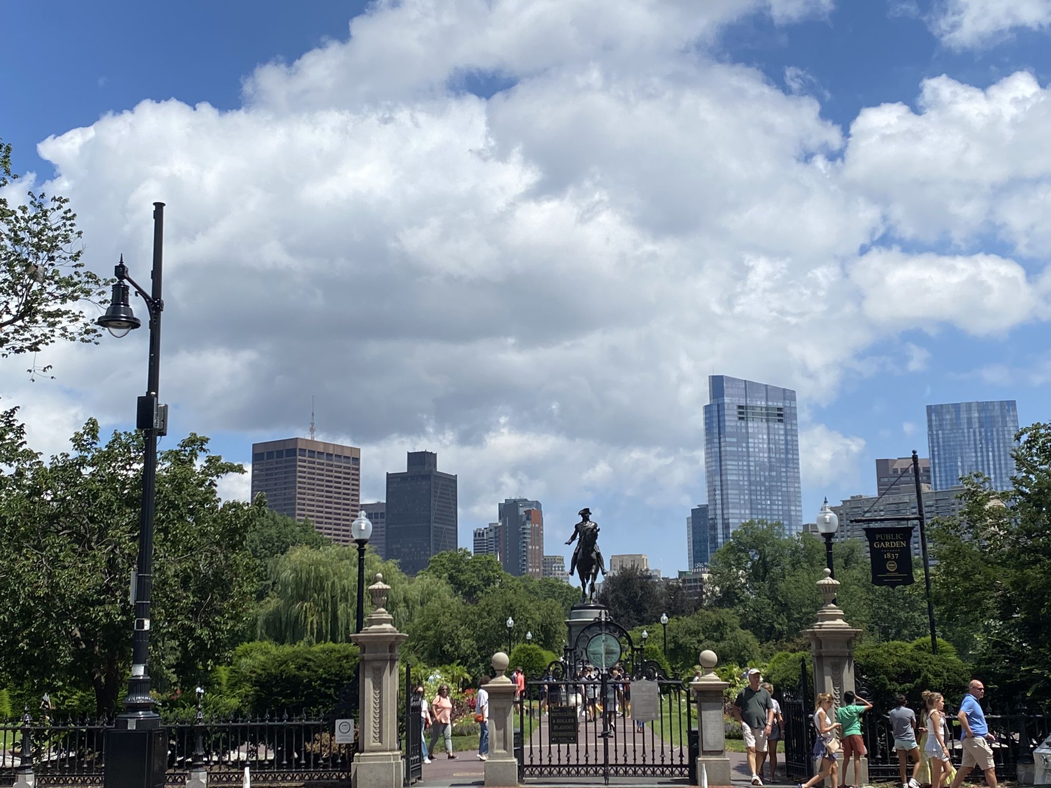Statue of a person on horseback, city skyline, and people, cloudy day. - From Blue Hills to Downtown