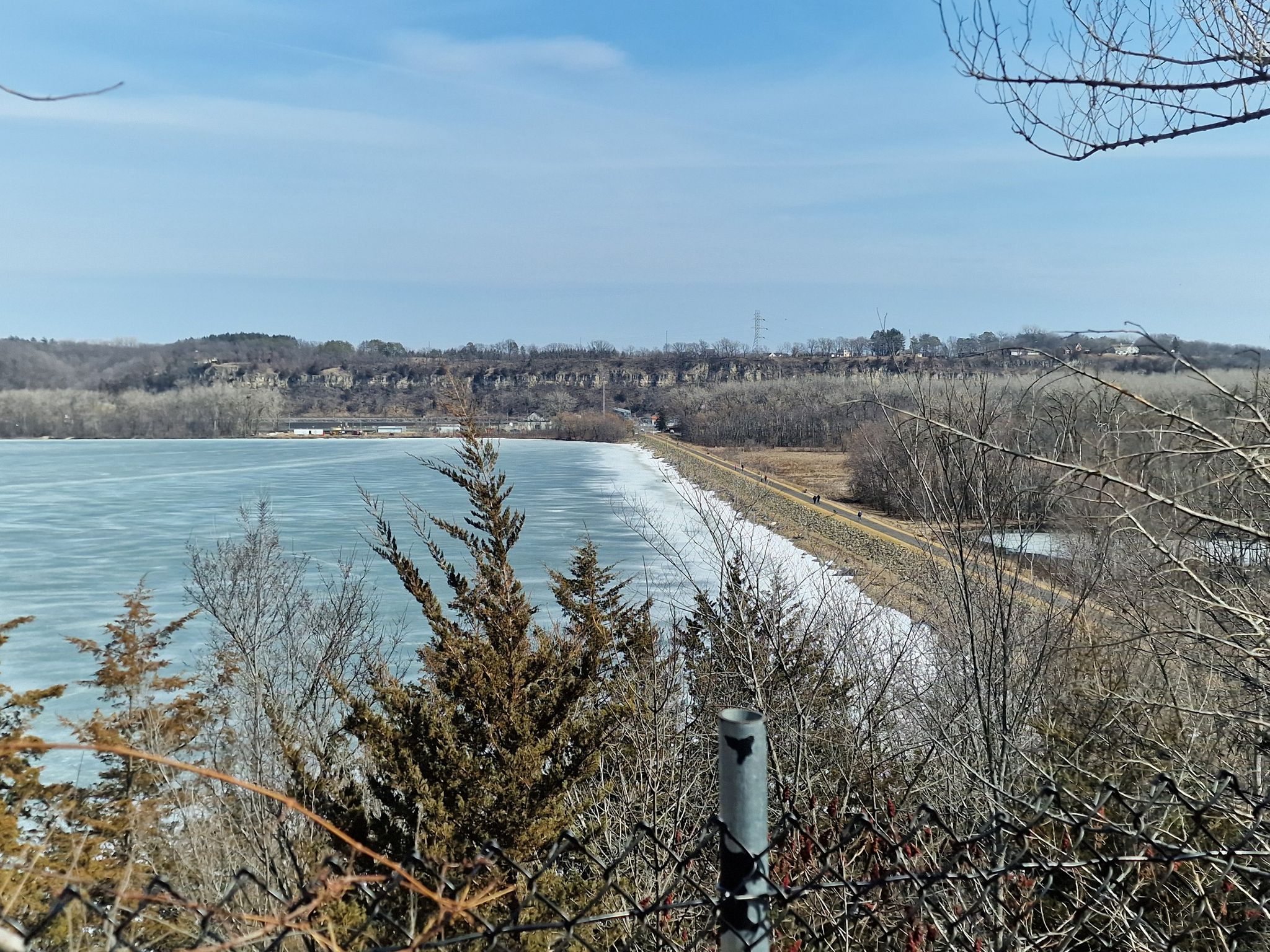 Icy lake next to an embankment with bare trees under a bright sky. - View of Lake Rebecca – Top of a long climb (Hastings) loop from Hastings