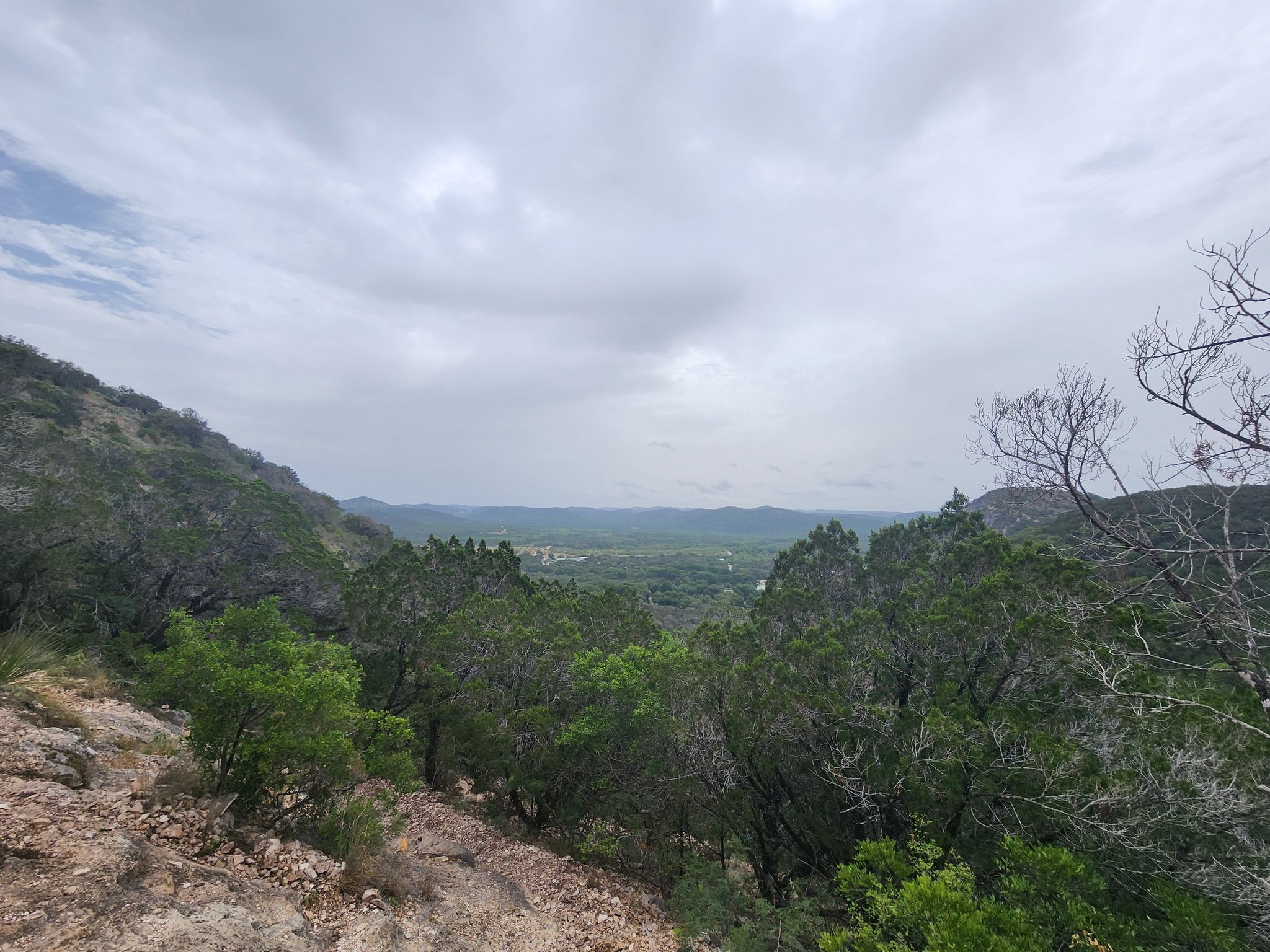 Overcast view of a green valley and distant hills from a rocky overlook. - Crystal Cave loop from Ol' Baldy